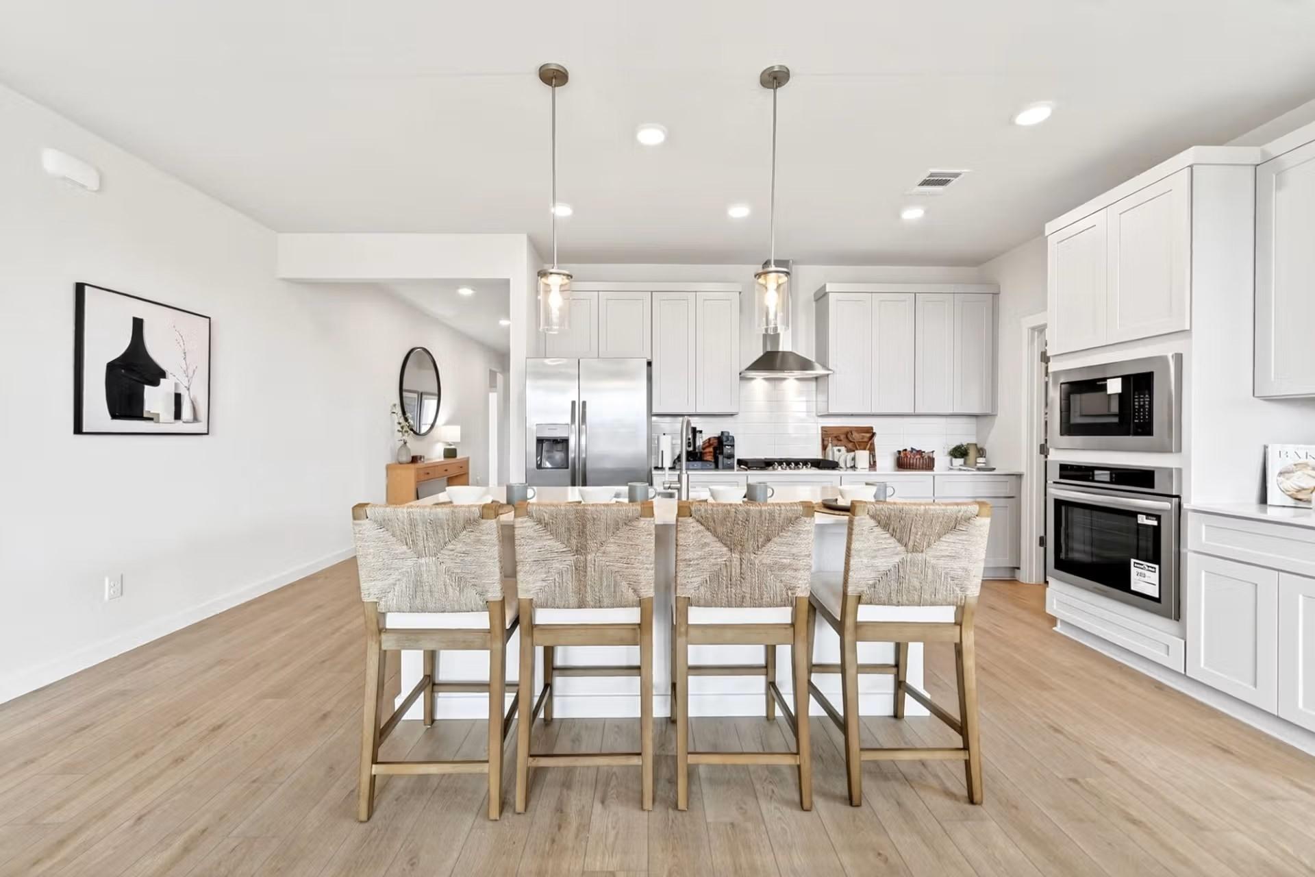 Modern kitchen with island seating, stainless appliances, and white cabinets in The Laurel I floor plan, Heartland, TX.