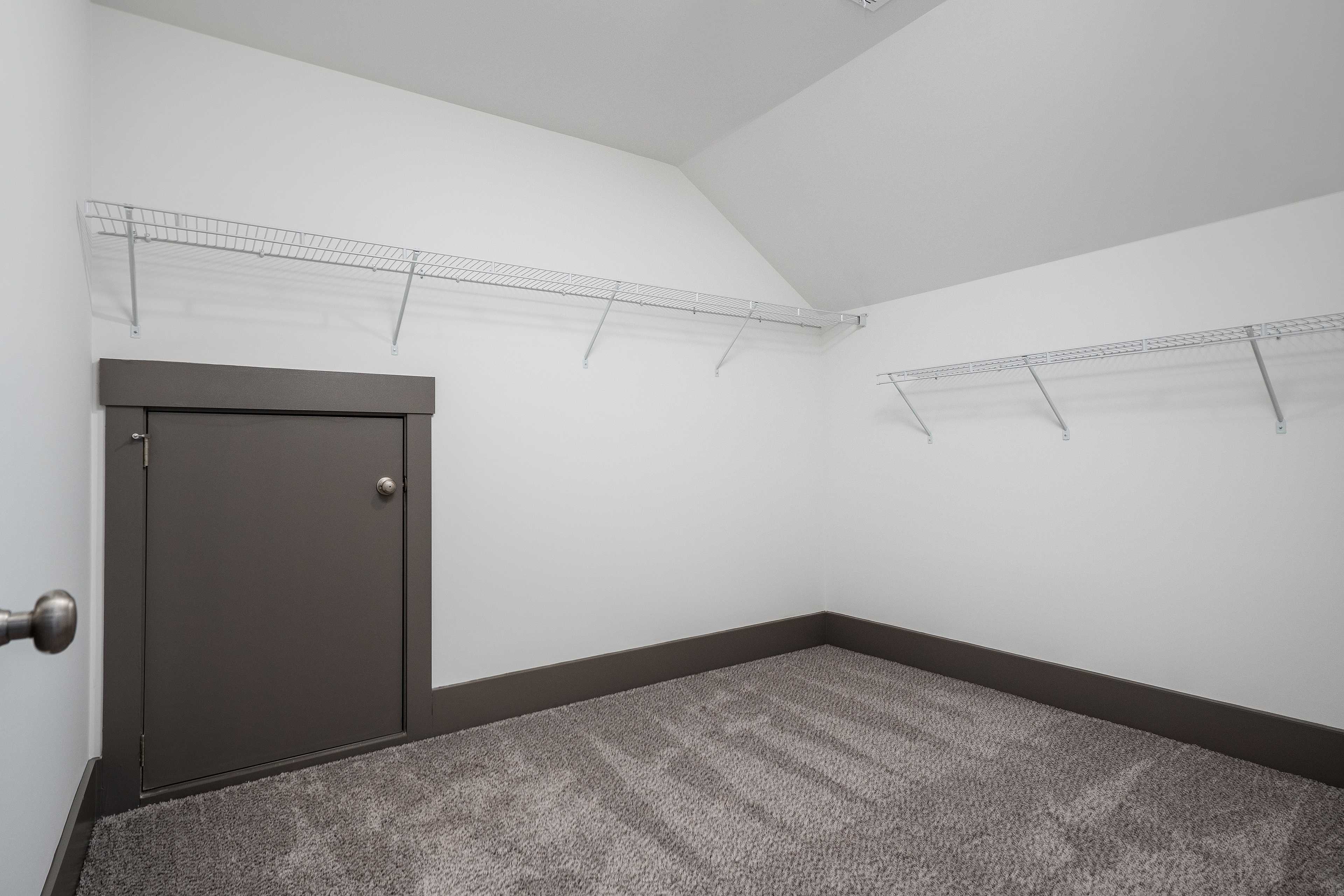Spacious walk-in closet with wire shelving, gray carpet floor, and dark gray door in Barnett's Crossing, Madison Alabama