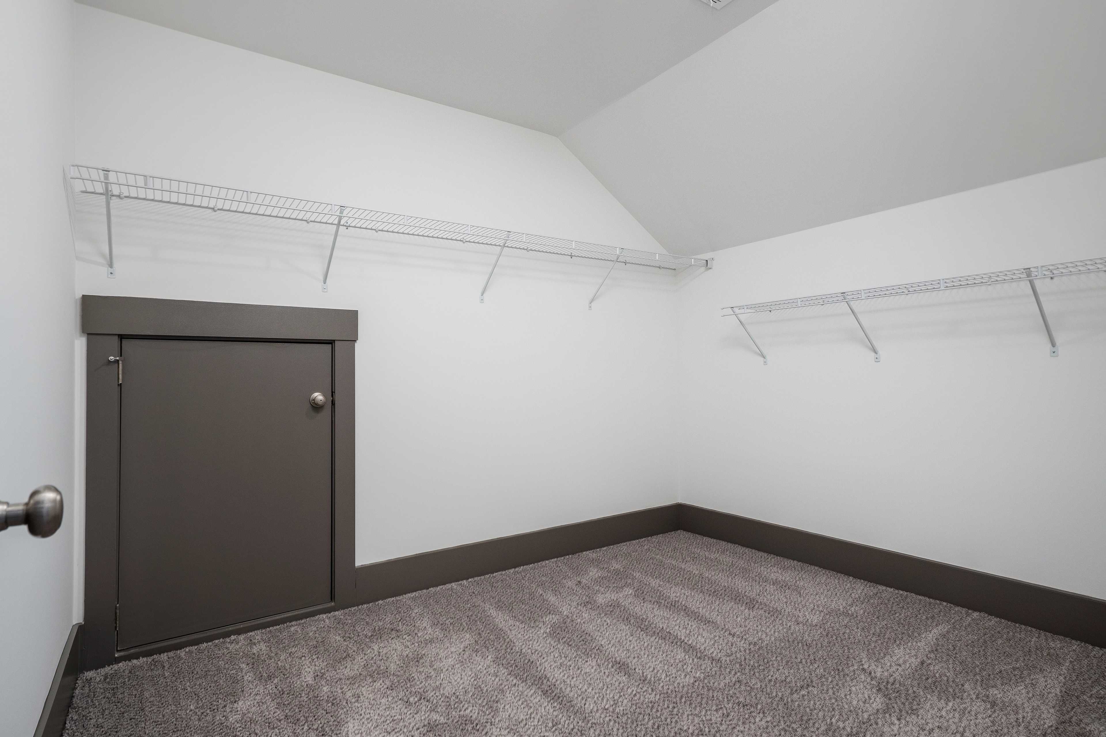 Spacious walk-in closet with wire shelving, gray carpet floor, and dark gray door in Barnett's Crossing, Madison Alabama