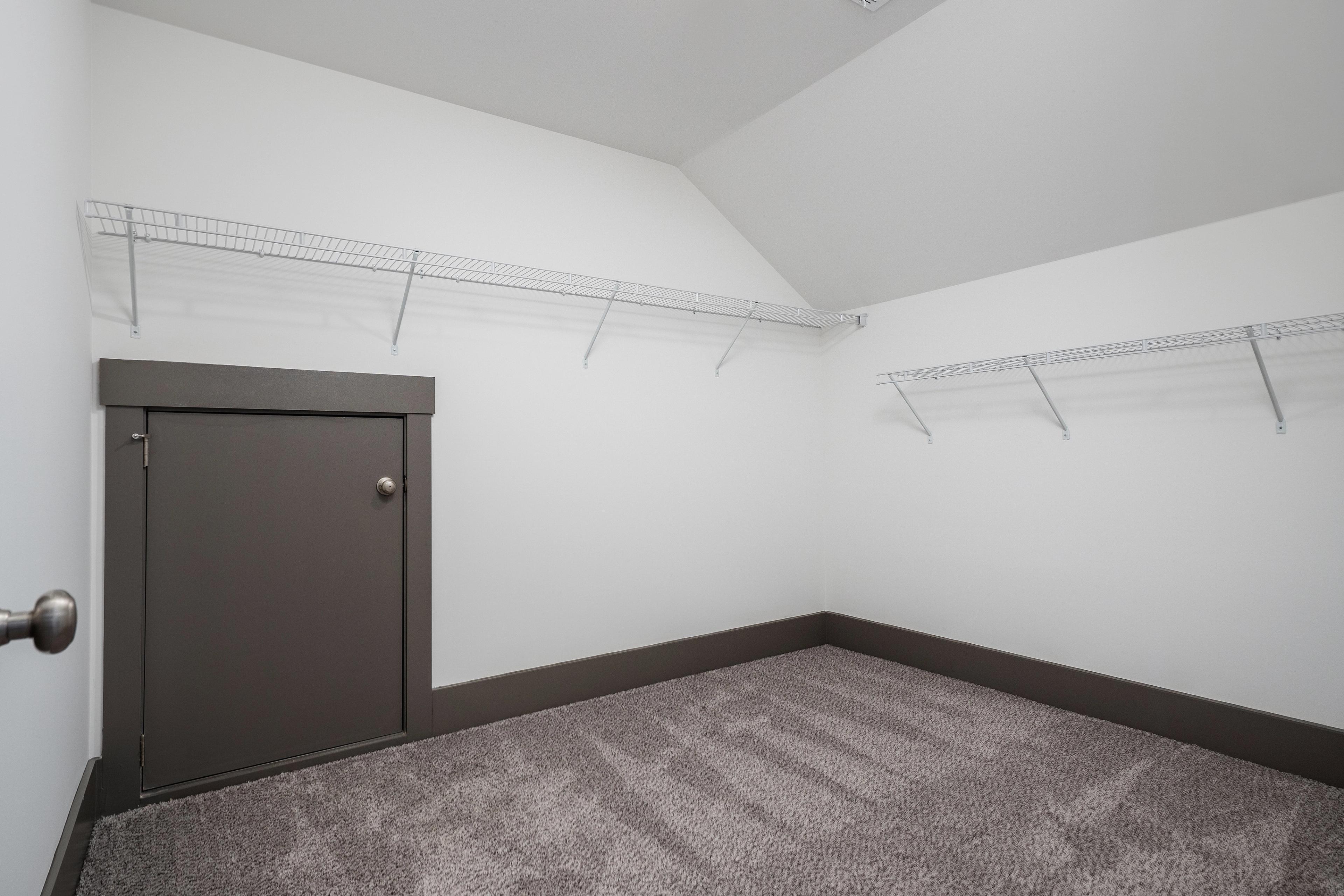 Spacious walk-in closet with wire shelving, gray carpet floor, and dark gray door in Barnett's Crossing, Madison Alabama