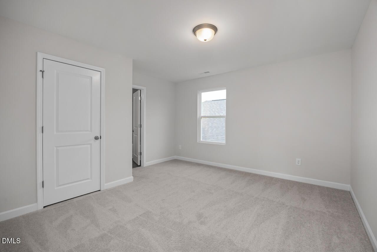 Spacious secondary bedroom with gray carpet, white doors, and window in 3-bedroom Gavin B home, Gregory Village, Lillington, NC