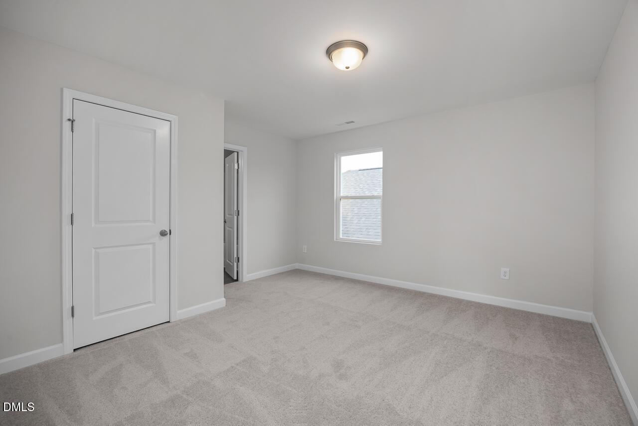 Spacious secondary bedroom with gray carpet, white doors, and window in 3-bedroom Gavin B home, Gregory Village, Lillington, NC