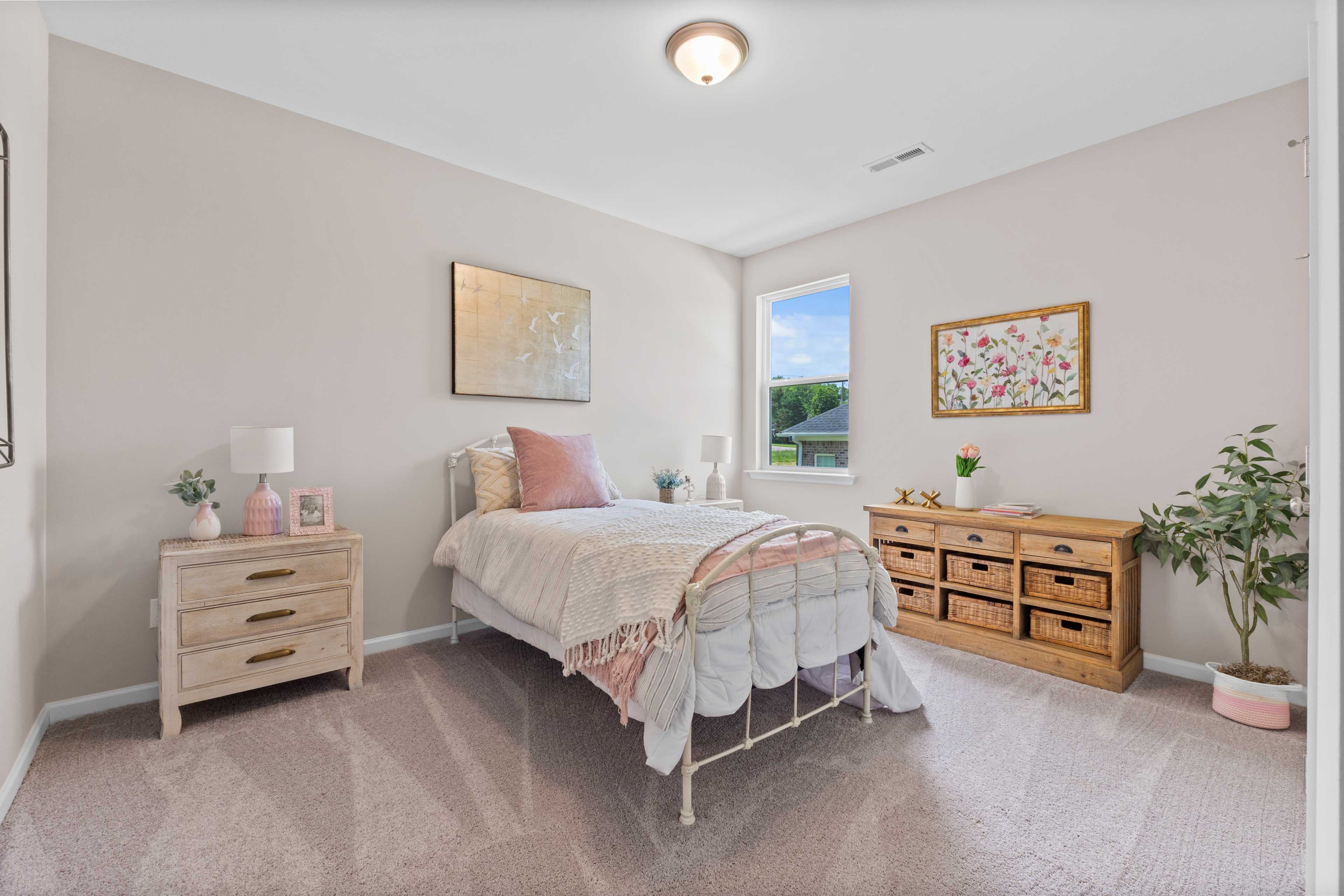 Cozy bedroom interior at Riverton Preserve in Huntsville, Alabama featuring vintage iron bed, pink bedding, and beige walls