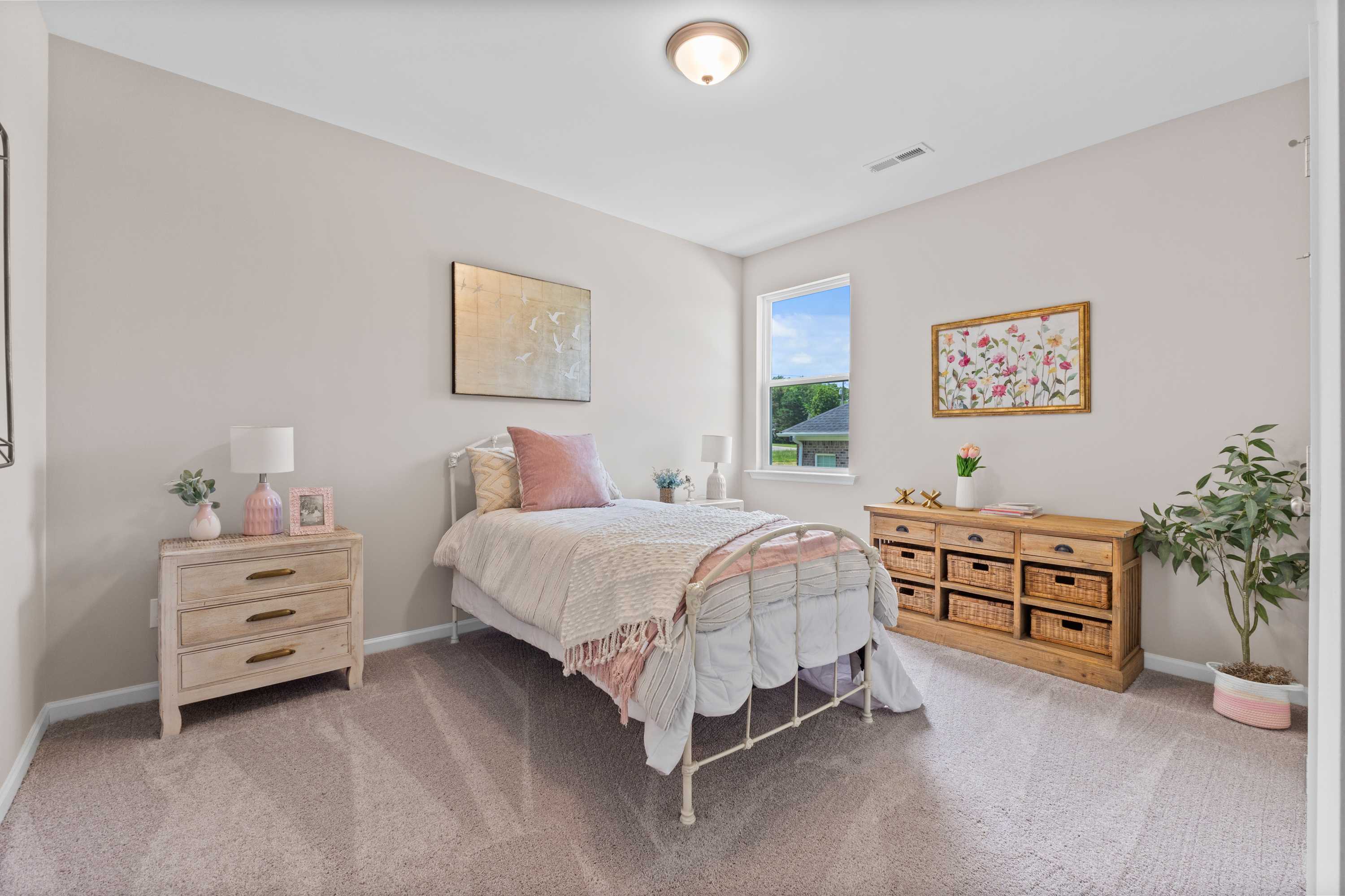 Cozy bedroom interior at Riverton Preserve in Huntsville, Alabama featuring vintage iron bed, pink bedding, and beige walls
