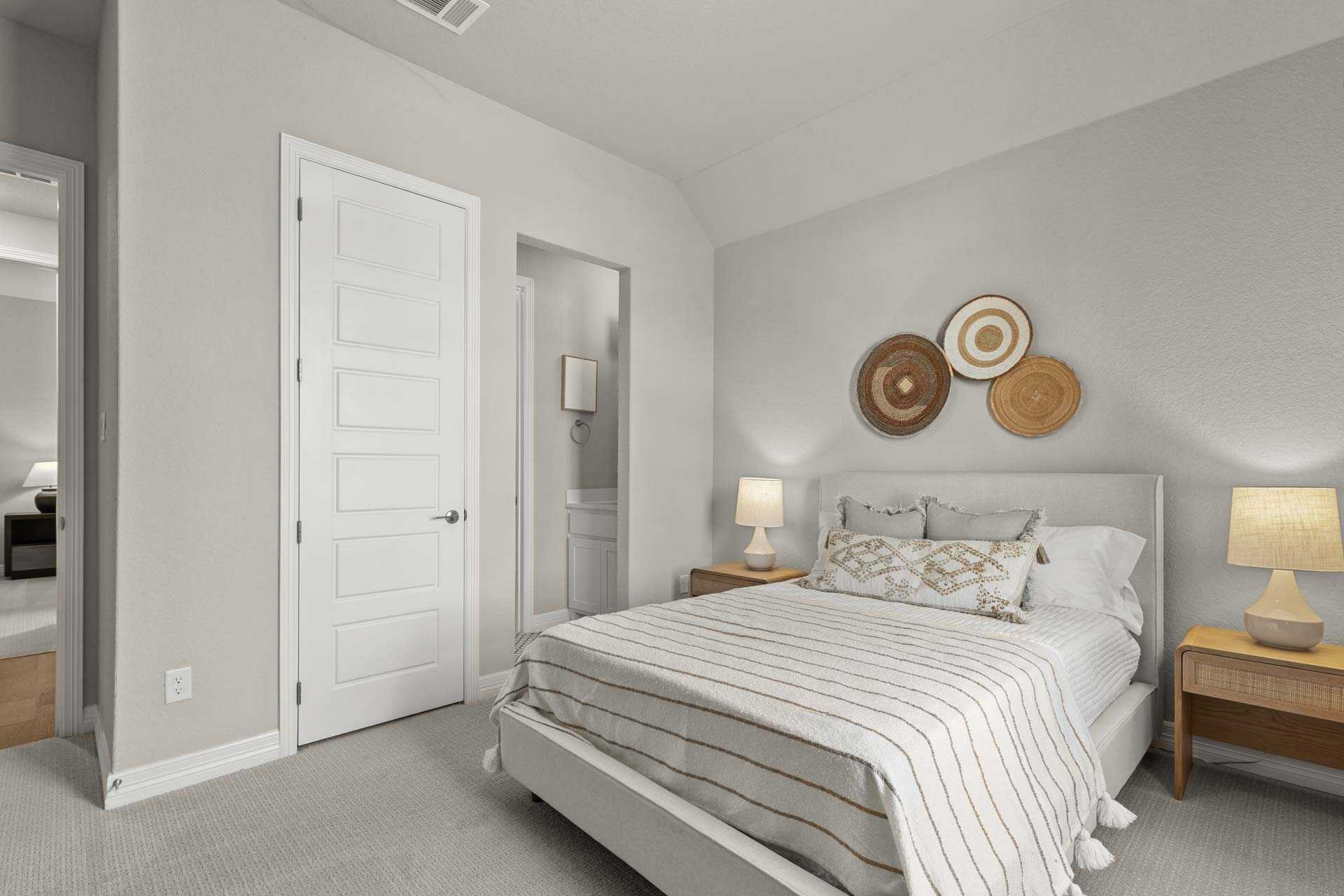 Serene master bedroom in The Summerlin B with light gray walls, king bed in striped bedding, woven wall baskets, and ensuite door