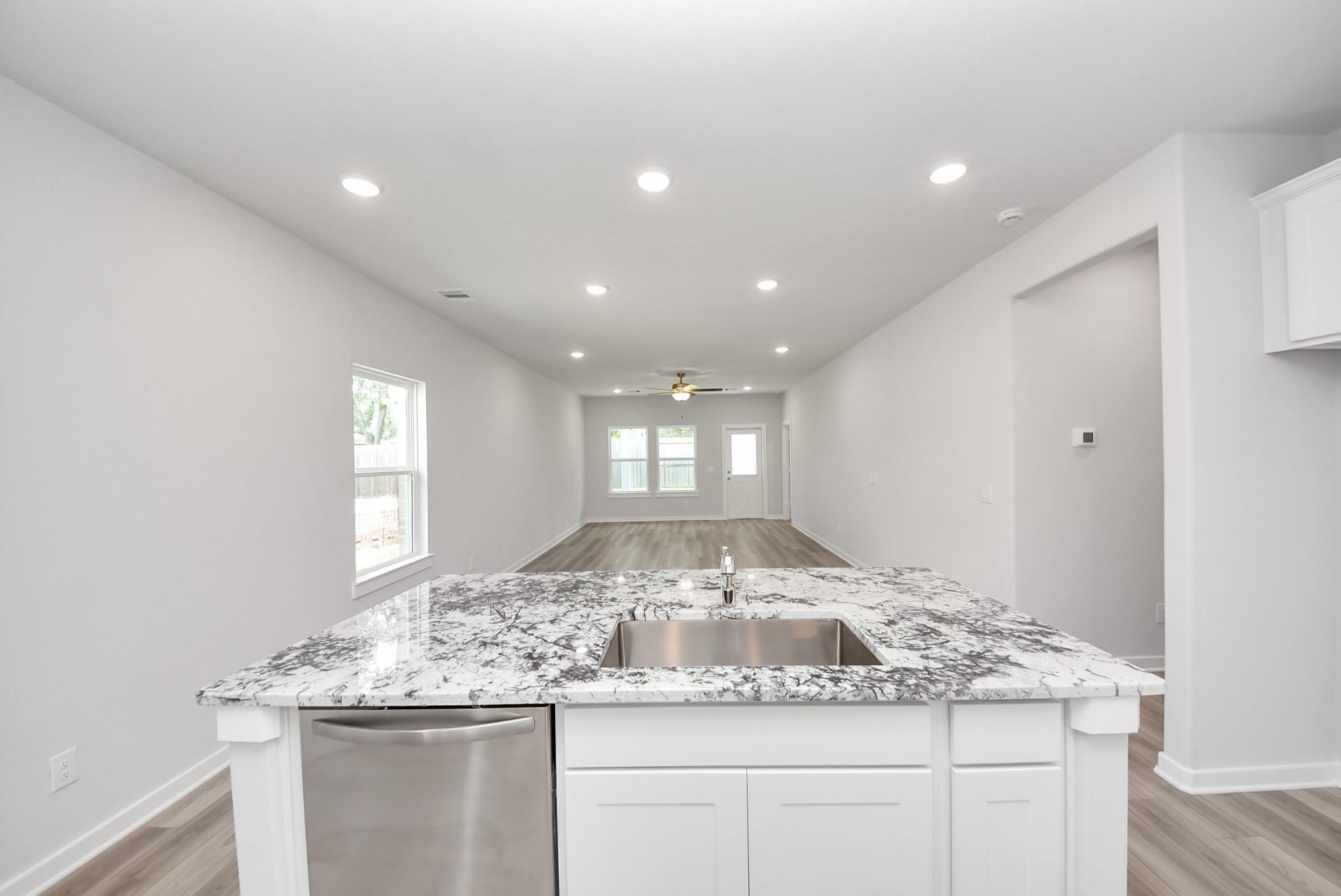 Open kitchen island with granite countertops in The Sabine E floor plan at Windmill Estates, Magnolia, Texas.