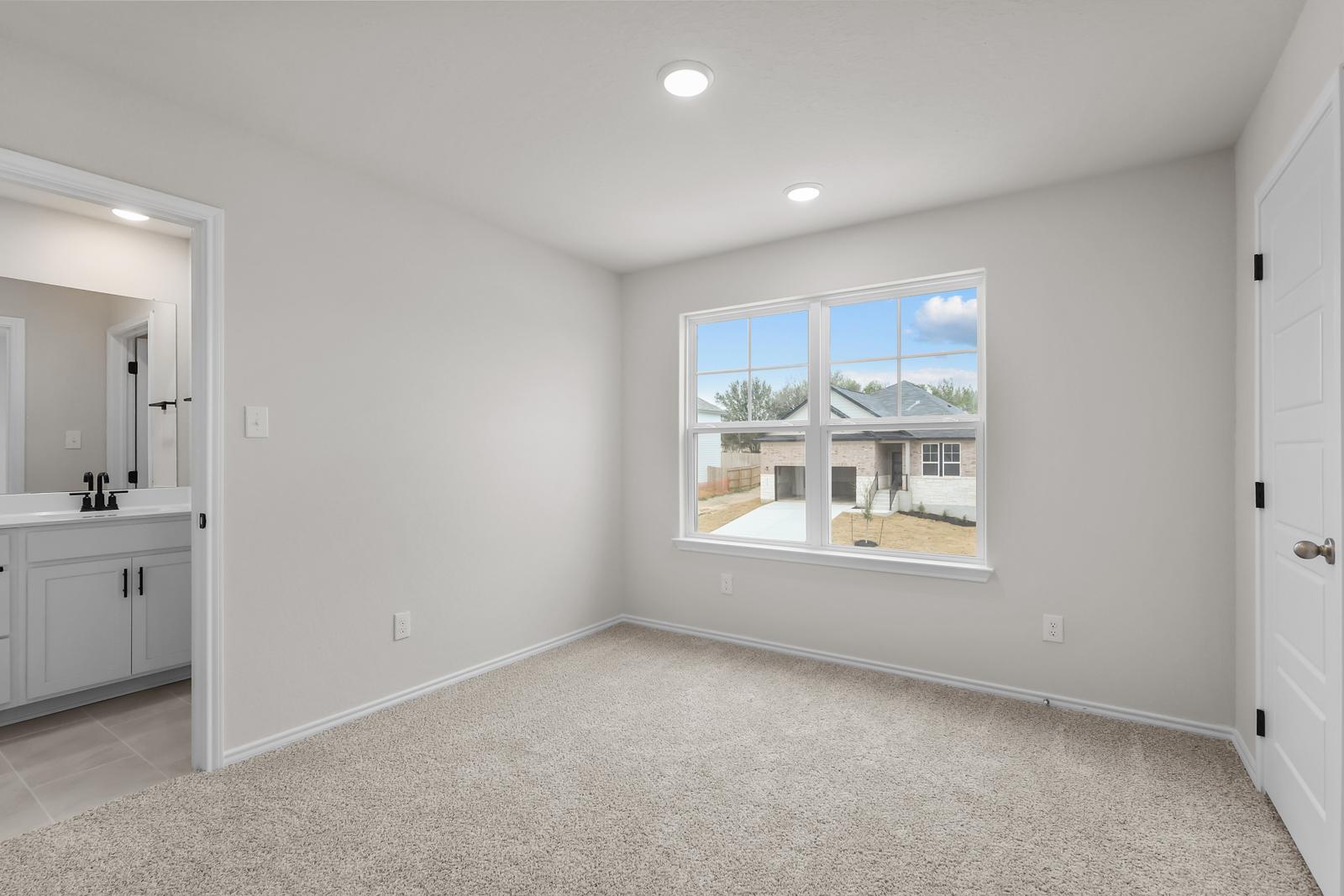 Spacious bedroom in The Sequoia C floor plan featuring plush carpeting, recessed lighting, and an attached ensuite bath.
