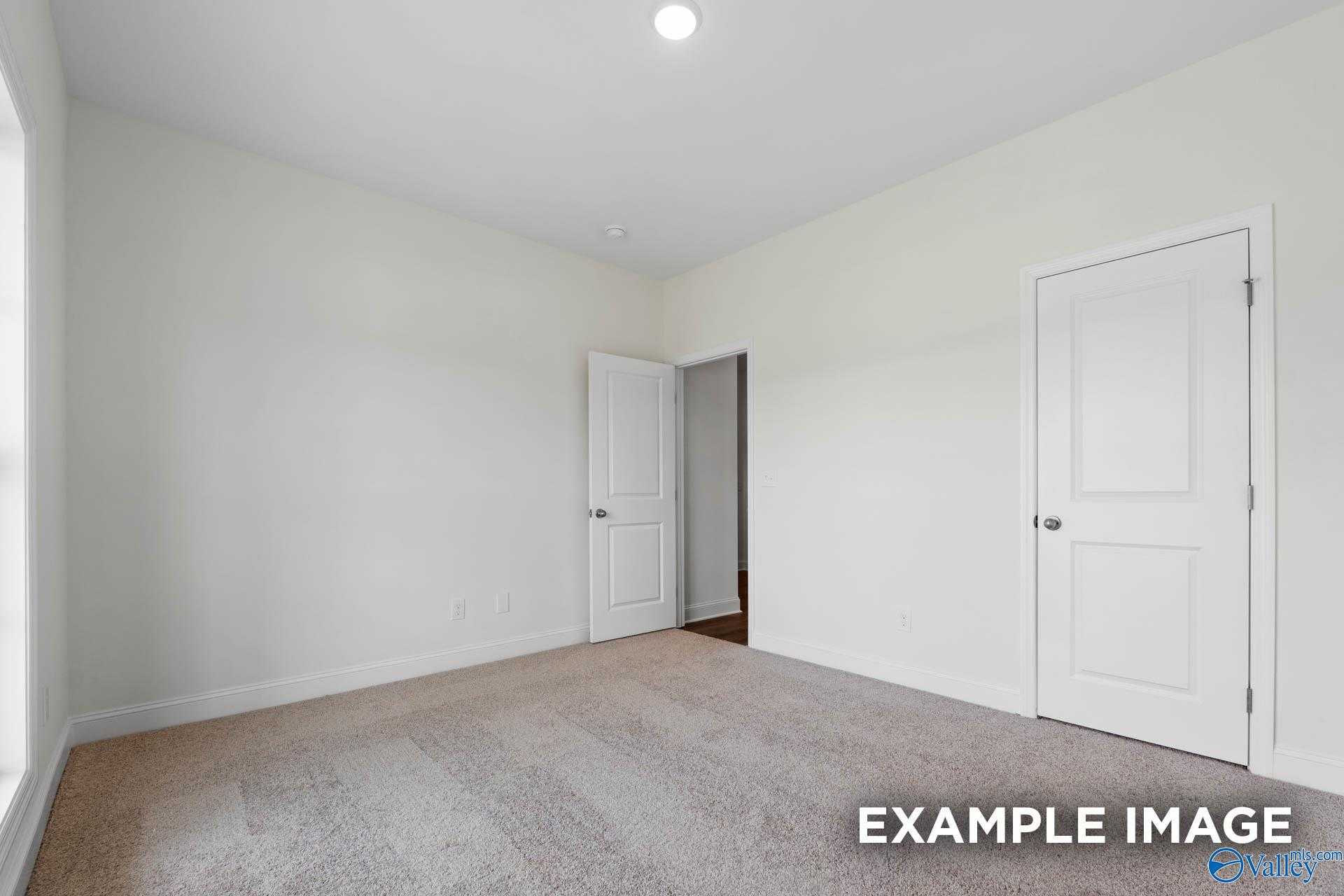 Spacious secondary bedroom with beige carpet, white walls, double doors and large window in Davidson Homes The Daphne D, Athens, Alabama