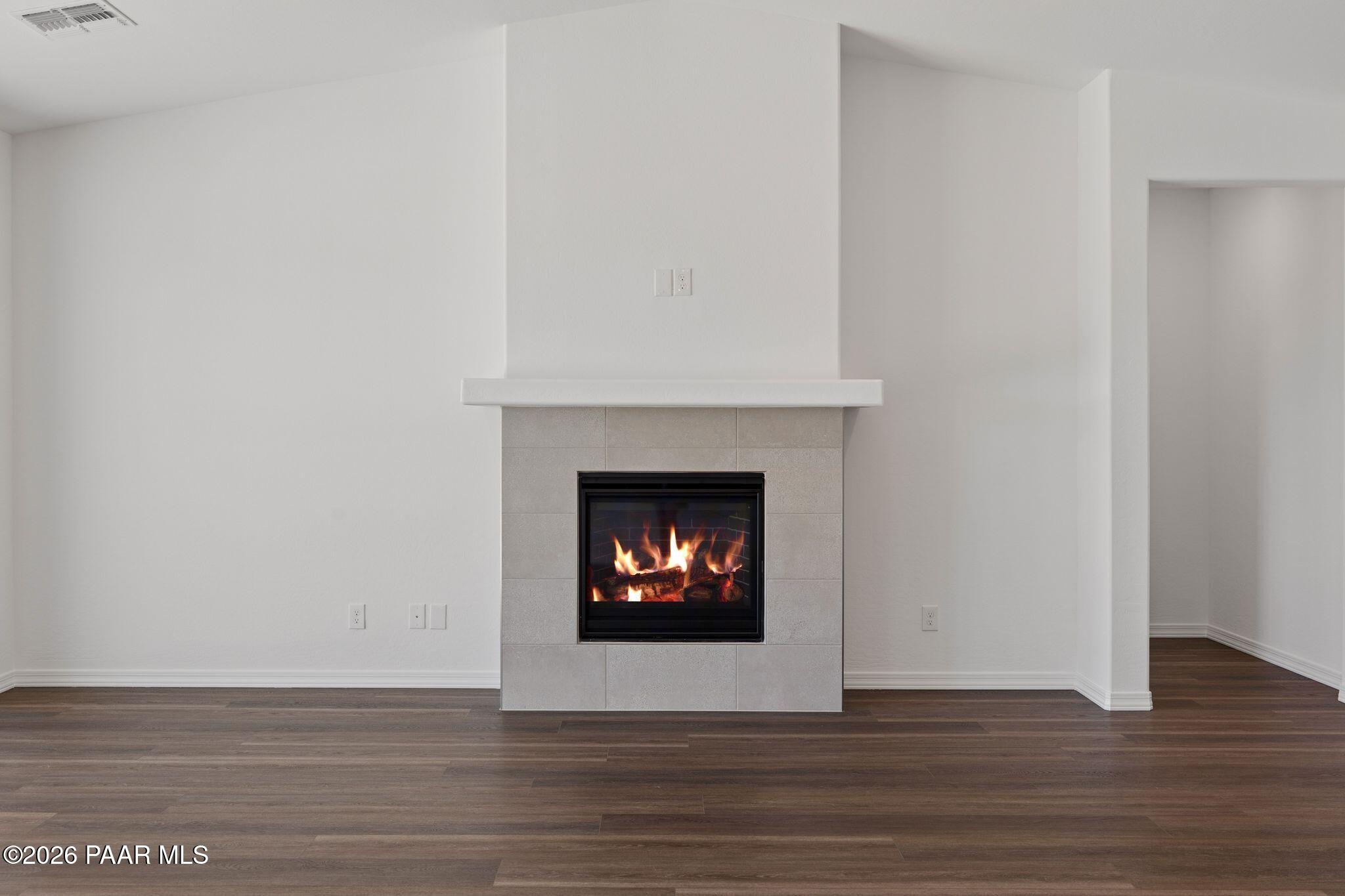 Cozy gas fireplace with stone mantel and flames in open living room, hardwood floors, Davidson Homes The Monarch A, Prescott AZ