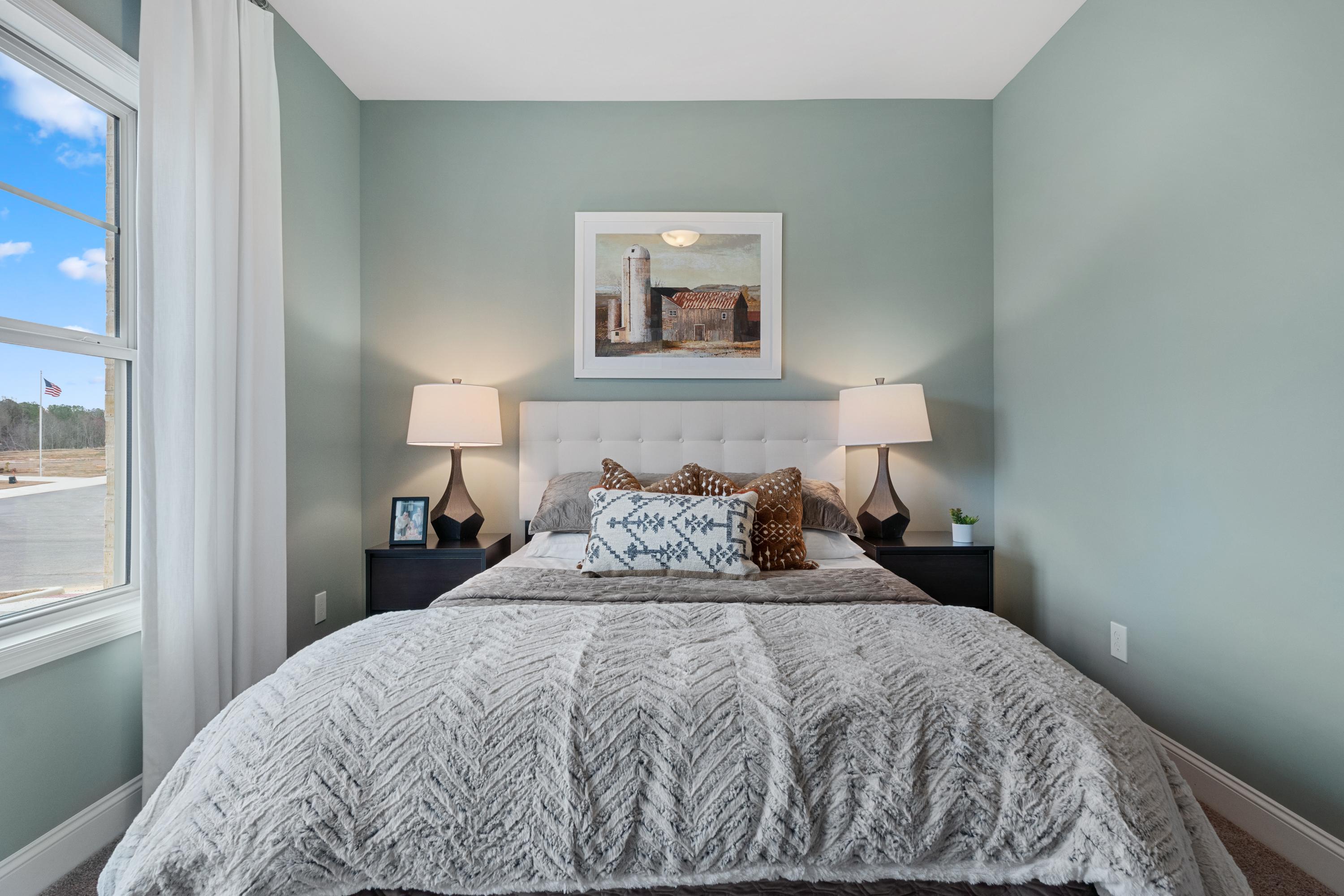 Serene sage green bedroom at The Retreat at Cain Park in Hartselle Alabama with white upholstered bed gray duvet and barn artwork