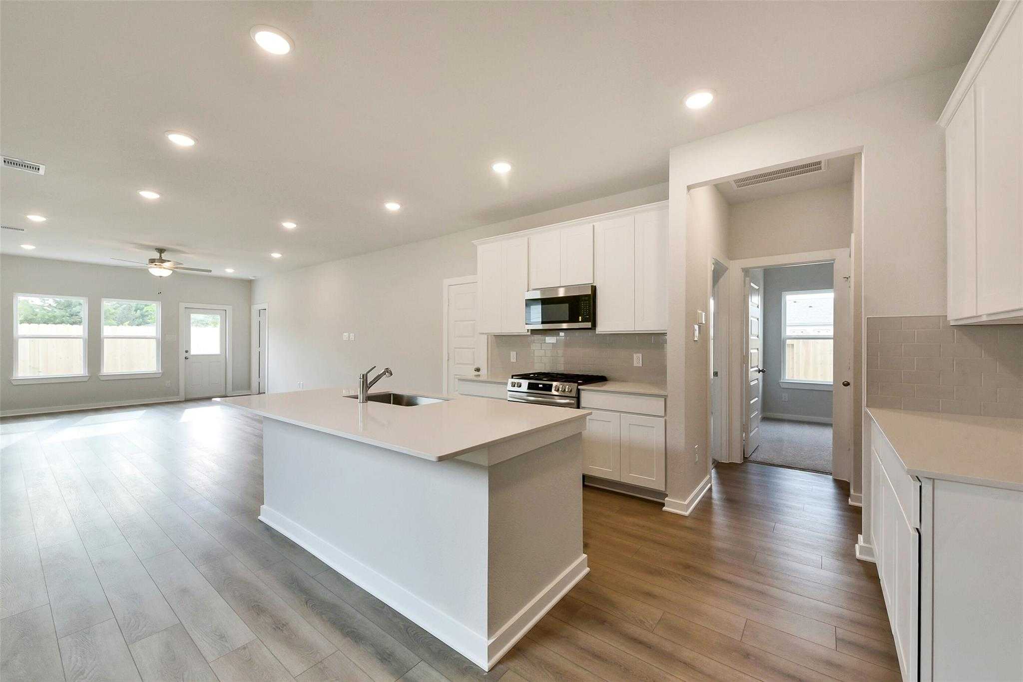 Modern open-concept kitchen with white shaker cabinets, quartz island, stainless appliances in The Frio G, Dayton, Texas