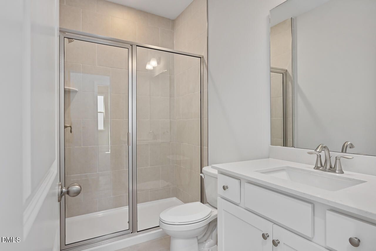 Modern bathroom with tiled walk-in shower and white vanity in The Adalynn B floor plan at Gregory Village, Lillington, NC.