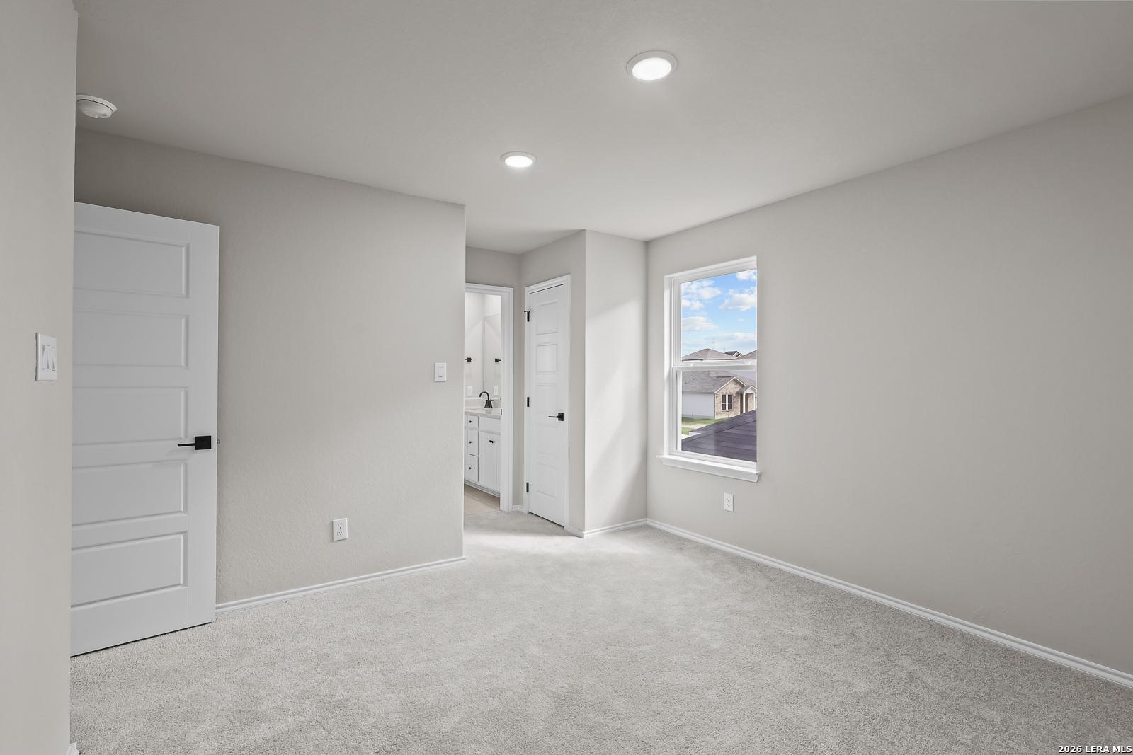 Bright bedroom with carpet, white doors, and window view in Davidson Homes The Sequoia C at Royal Crest, San Antonio, Texas