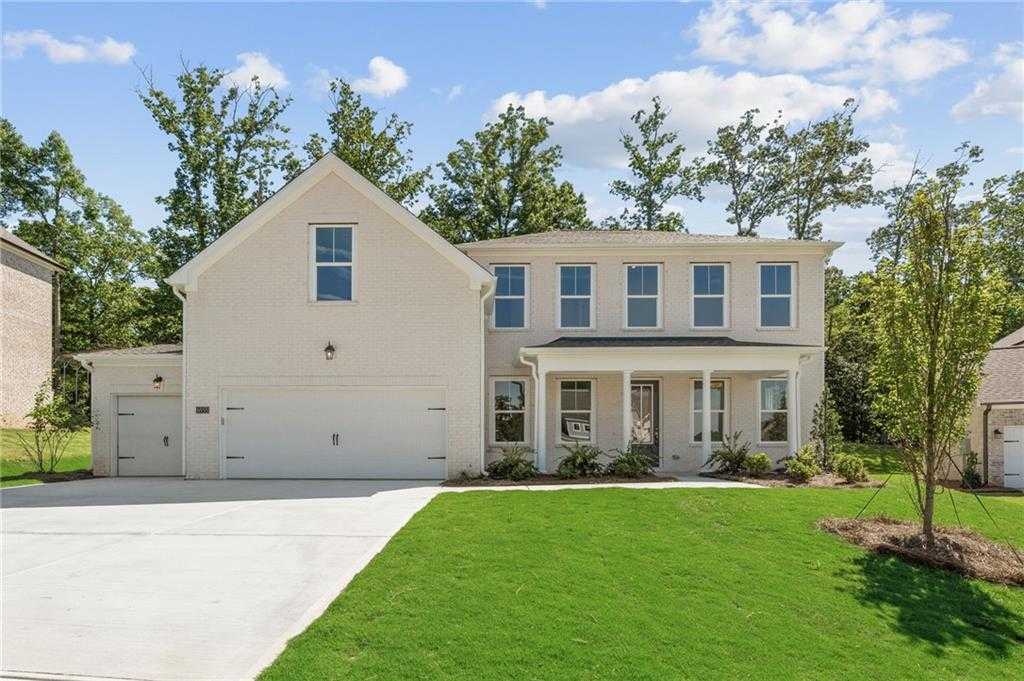 Two-story beige Craftsman home with gabled roof, covered porch, and three-car garage in Melody Lakeside Estates, Buford, Georgia