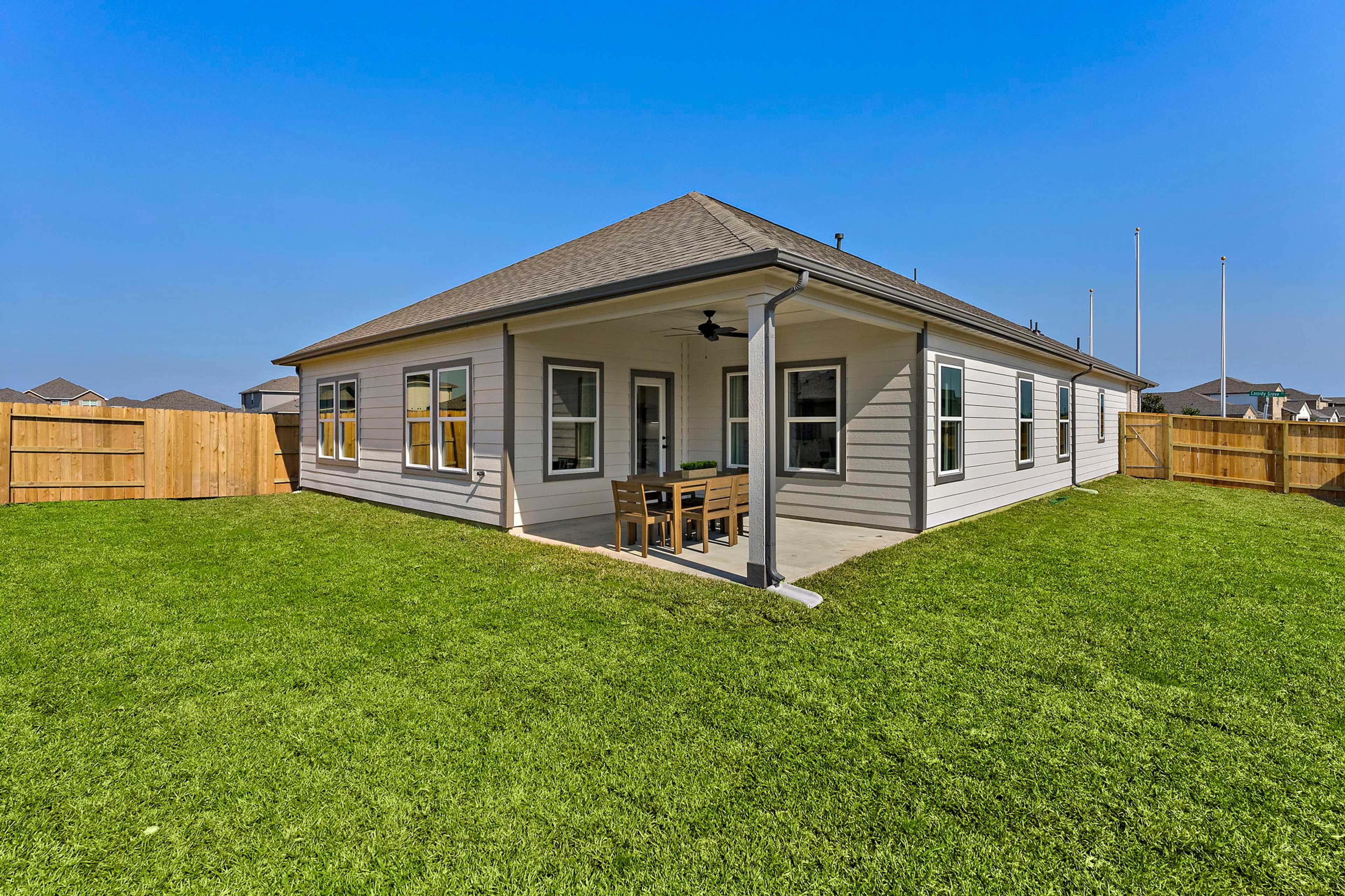 Modern single-story home at Sundance Cove in Crosby Texas with covered patio, ceiling fan, and outdoor dining by Davidson Homes
