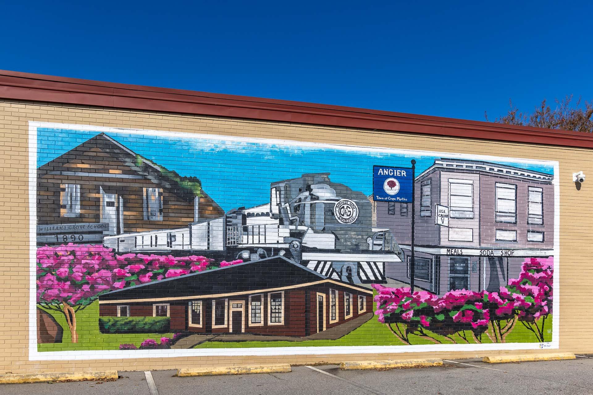 Vibrant mural of historic Angier NC steam train, wooden buildings, and pink azaleas on Tobacco Road community wall