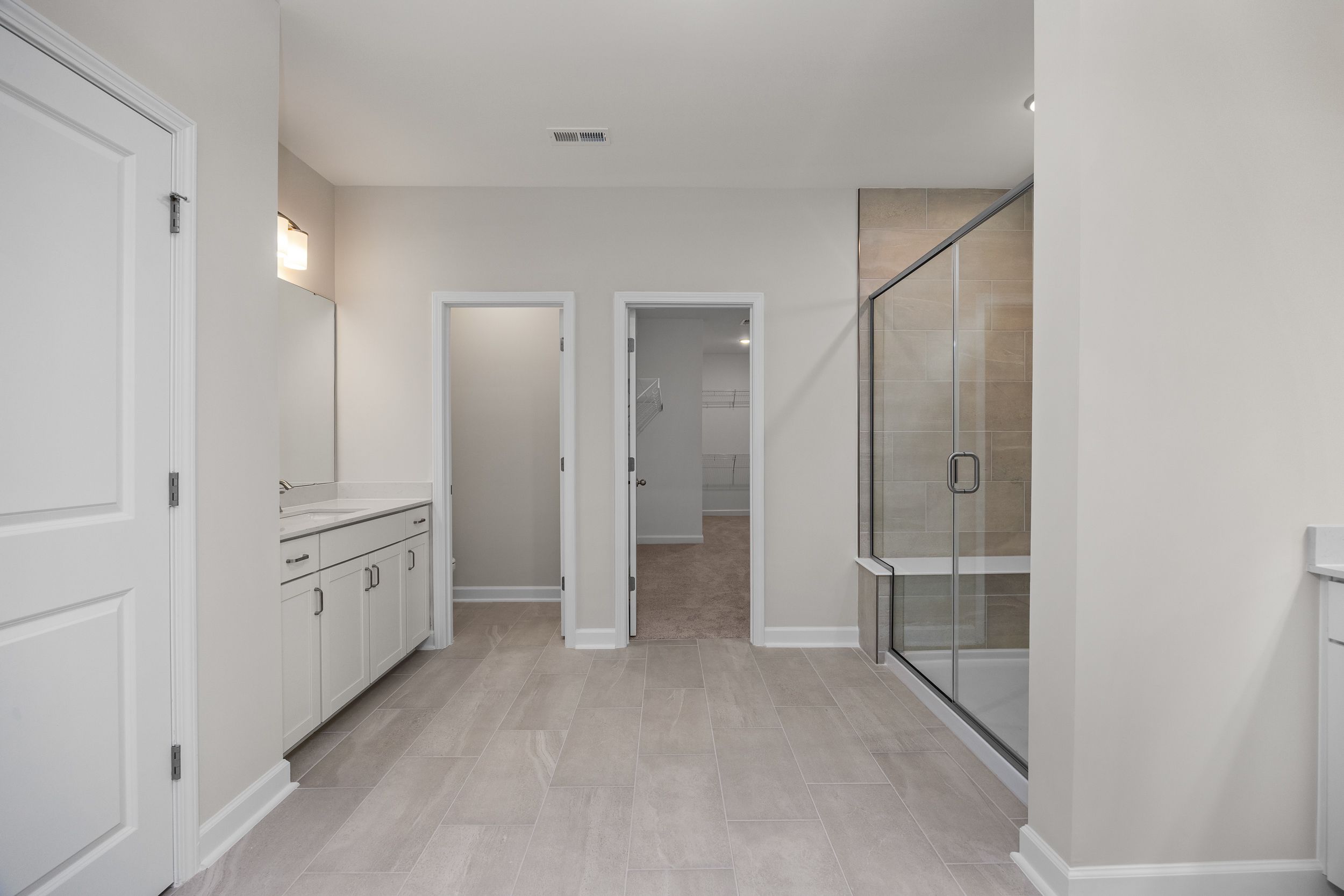 Master bathroom in The Aspen home design with double vanity, glass shower, and neutral tones