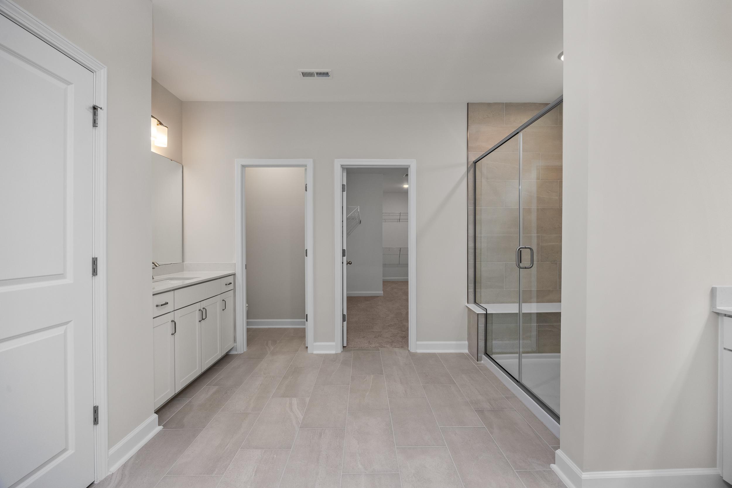 Master bathroom in The Aspen home design with double vanity, glass shower, and neutral tones