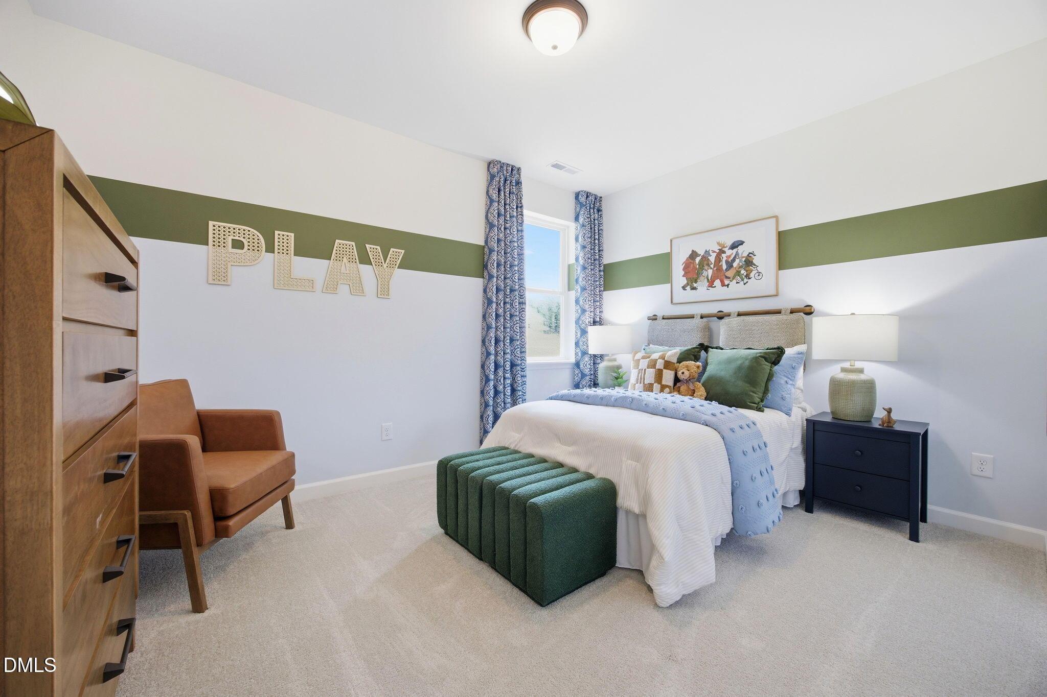 Cozy kids' bedroom with green accent wall and "PLAY" decor in The Ashport M floor plan at Wendell Ridge, North Carolina.
