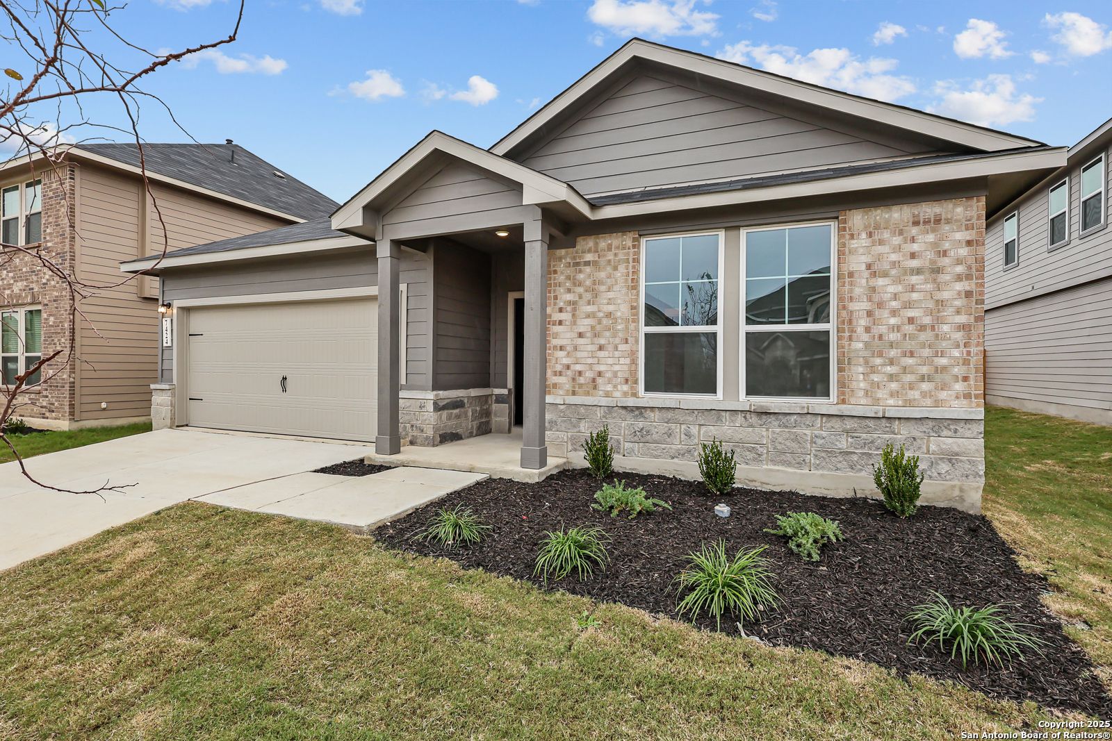 Modern 1-story 4-bedroom home with beige brick facade, gray siding, 2-car garage, covered porch, and landscaped yard in Horizon Pointe, Converse, Texas