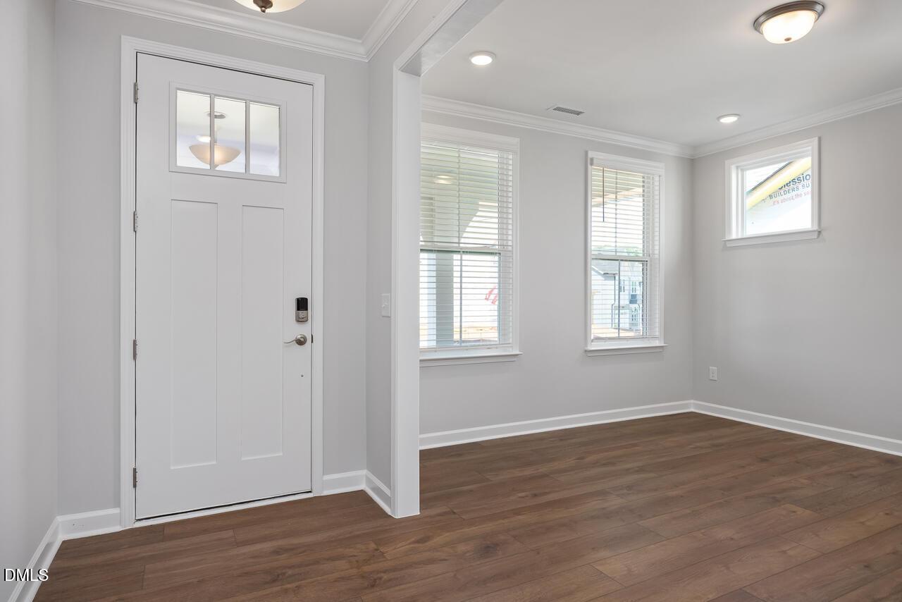Bright entryway with white door and wood-style flooring in The Ashport L plan at Sage on North Main, Wake Forest, NC.
