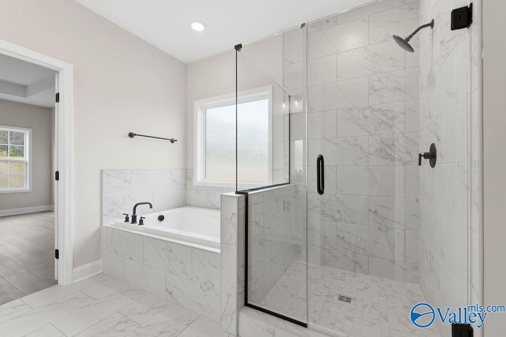 Elegant master bathroom with marble tiles, frameless glass shower, soaking tub in Davidson Homes The Rockford B, Hartselle AL