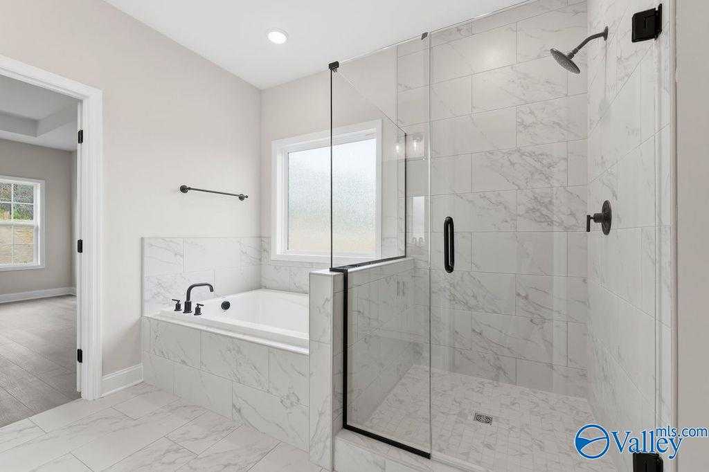 Elegant master bathroom with marble tiles, frameless glass shower, soaking tub in Davidson Homes The Rockford B, Hartselle AL