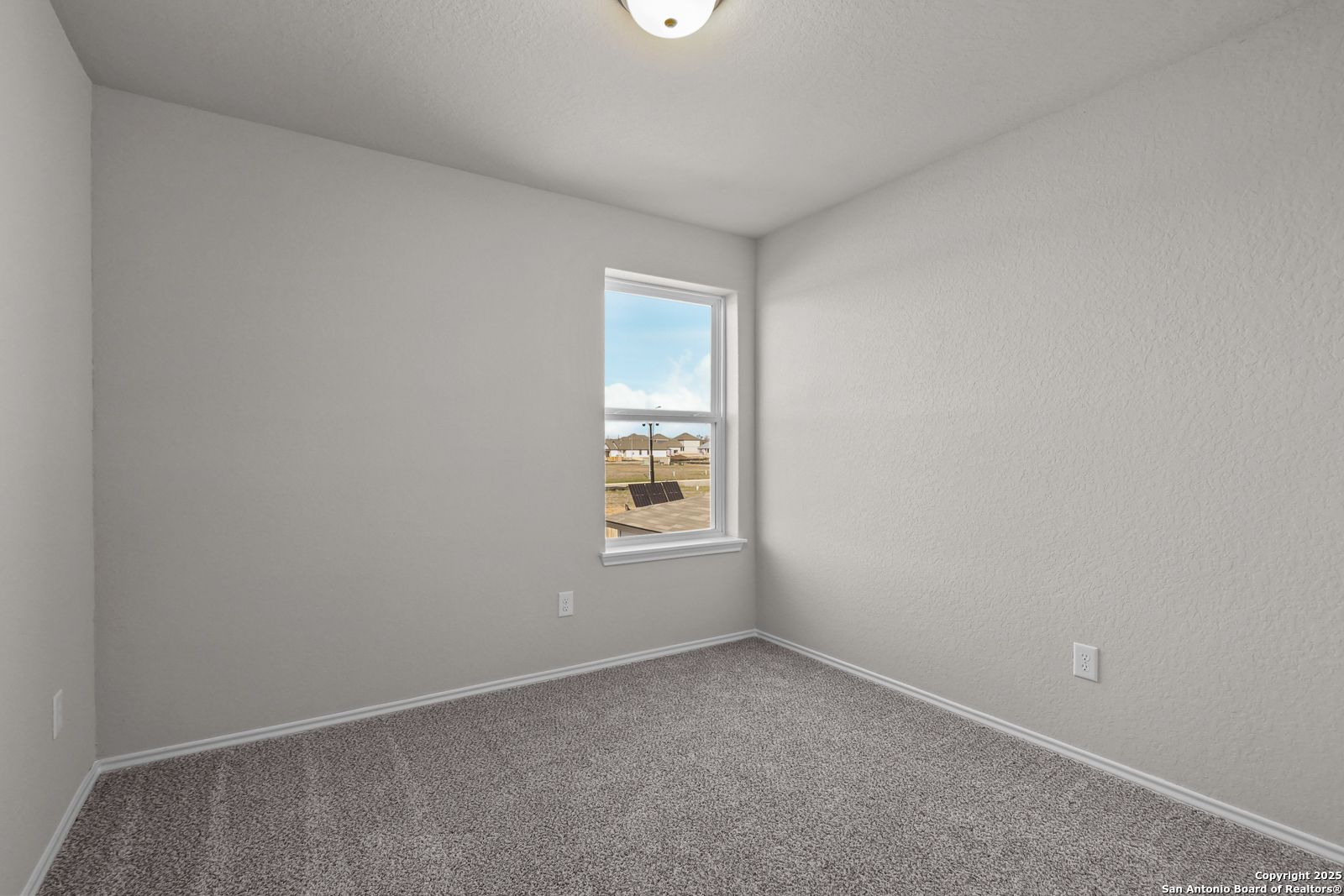 Bright secondary bedroom with neutral walls, carpet flooring, and large window in 5-bedroom Davidson Homes The Brazos C, San Antonio, Texas