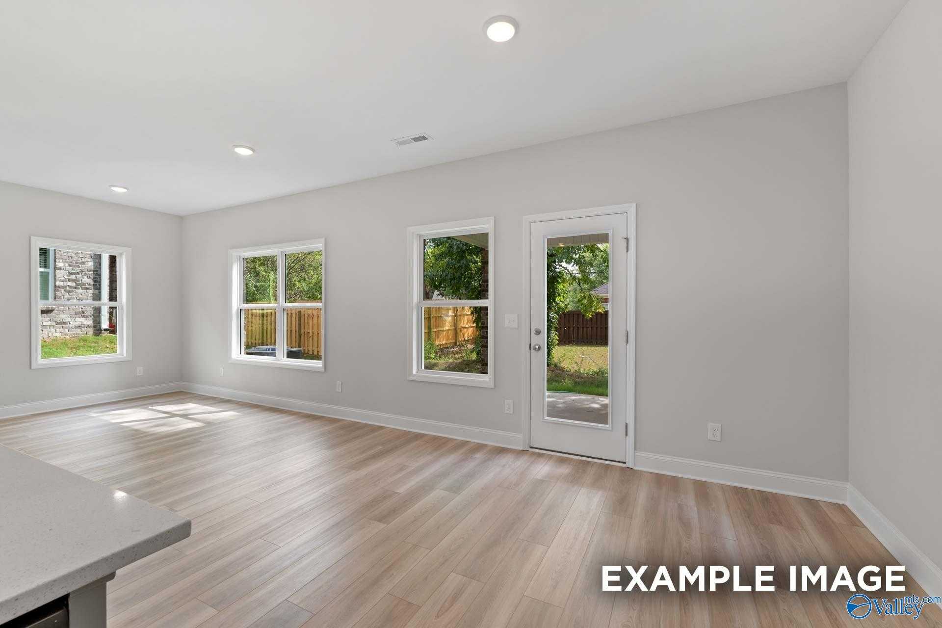 Spacious living room with hardwood floors, large windows, and French doors to backyard in Davidson Homes The Camden, Huntsville