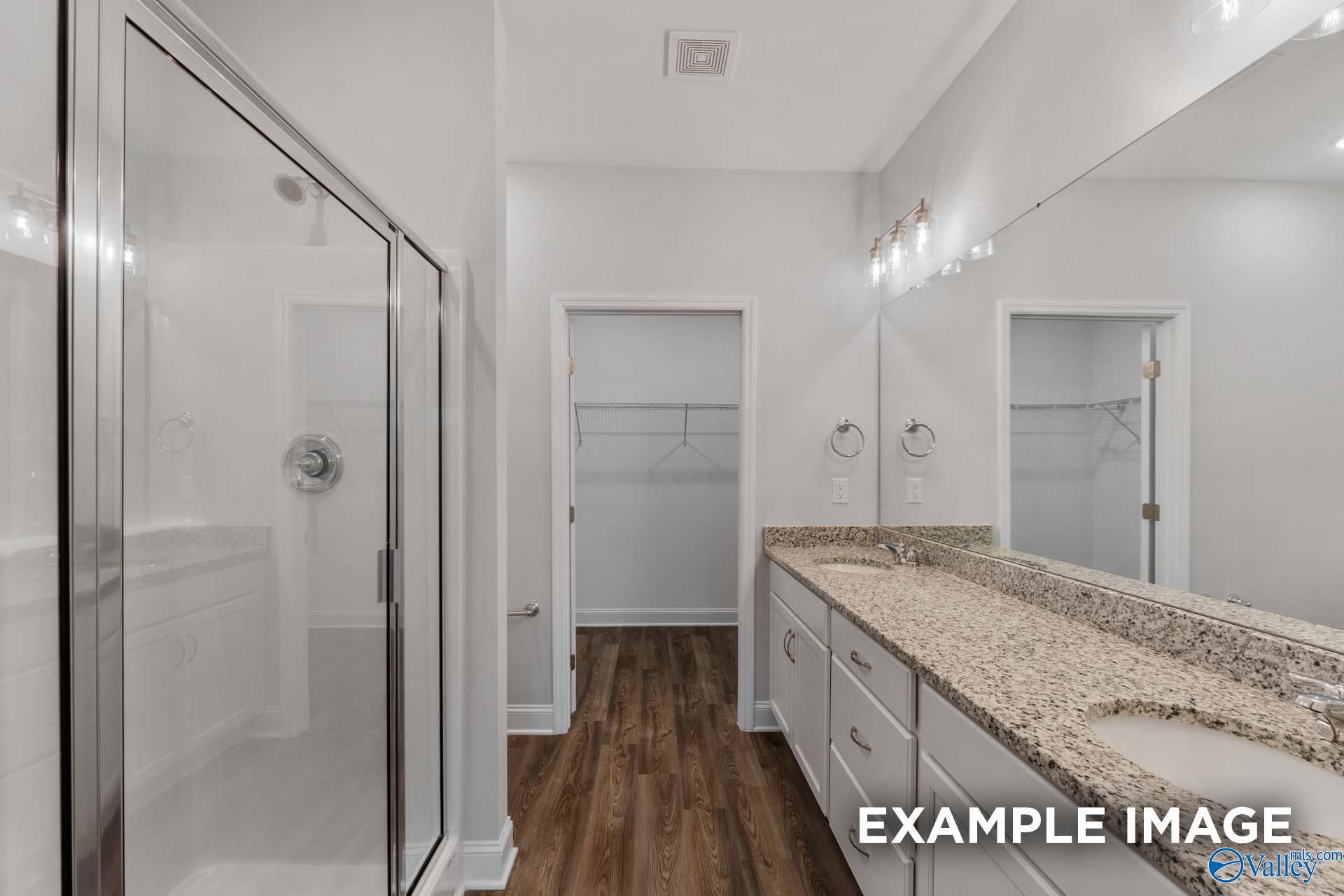 Modern master bathroom featuring glass shower, granite double vanity, and walk-in closet in Davidson Homes The Cumberland B, Decatur, Alabama
