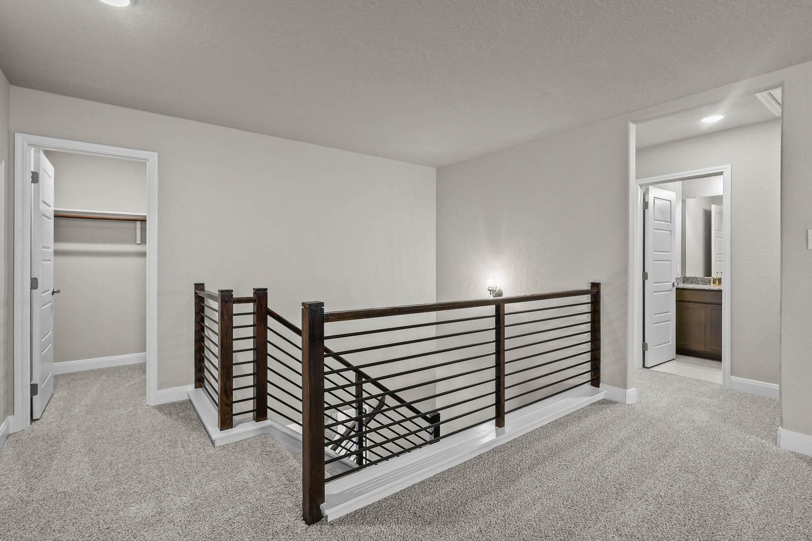 Second-floor landing in The Jennings G featuring modern metal railing, plush carpeting, and access to bedroom and bath.