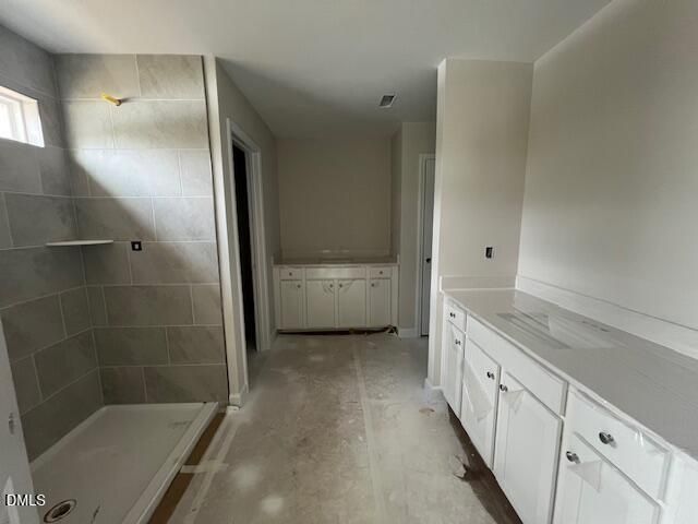 Spacious master bathroom with gray tiled walk-in shower, double white vanity, and quartz counters in The Preston A, Lillington, NC