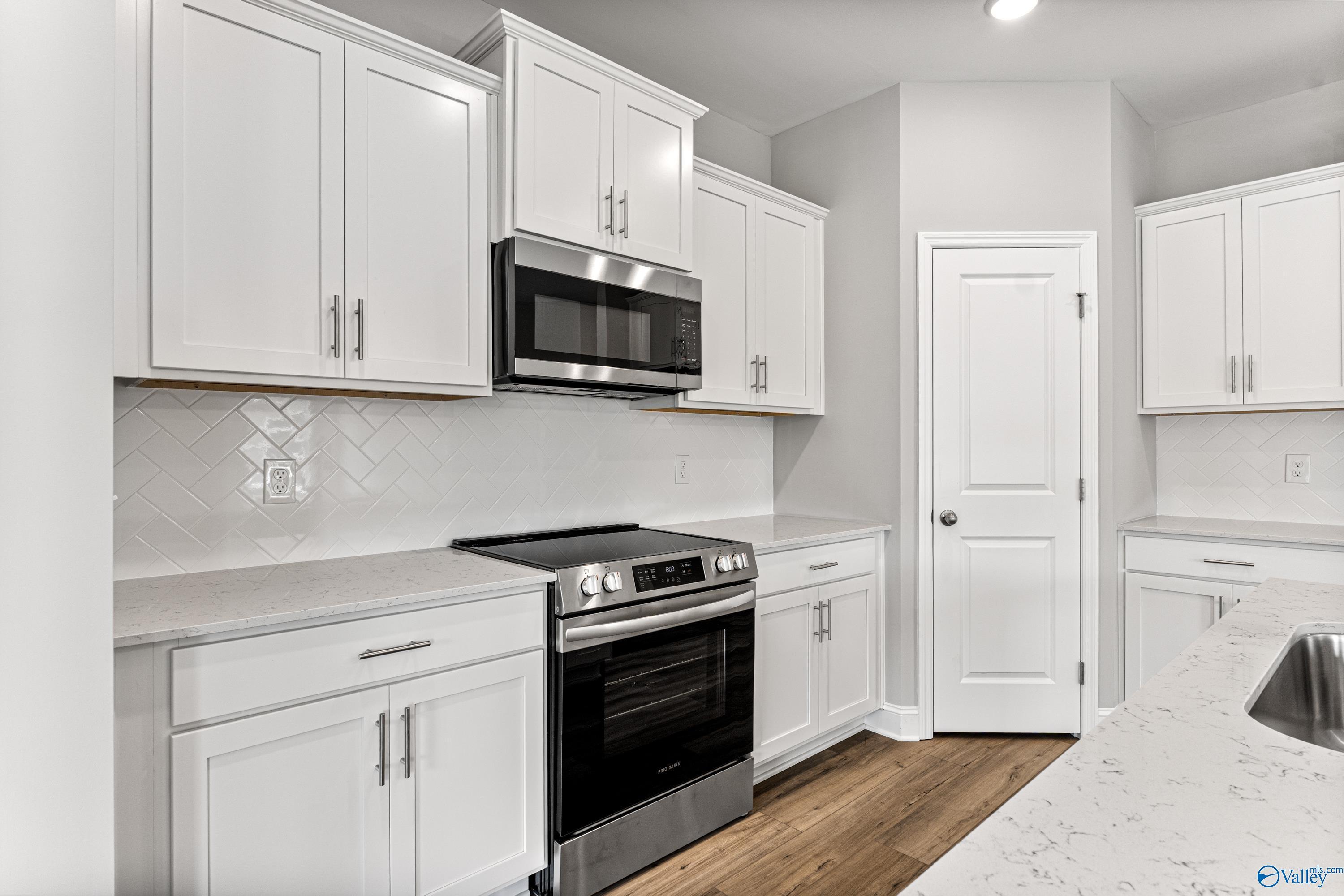 Modern white kitchen with stainless steel appliances, quartz countertops, subway tile backsplash in Davidson Homes Franklin C, Huntsville AL