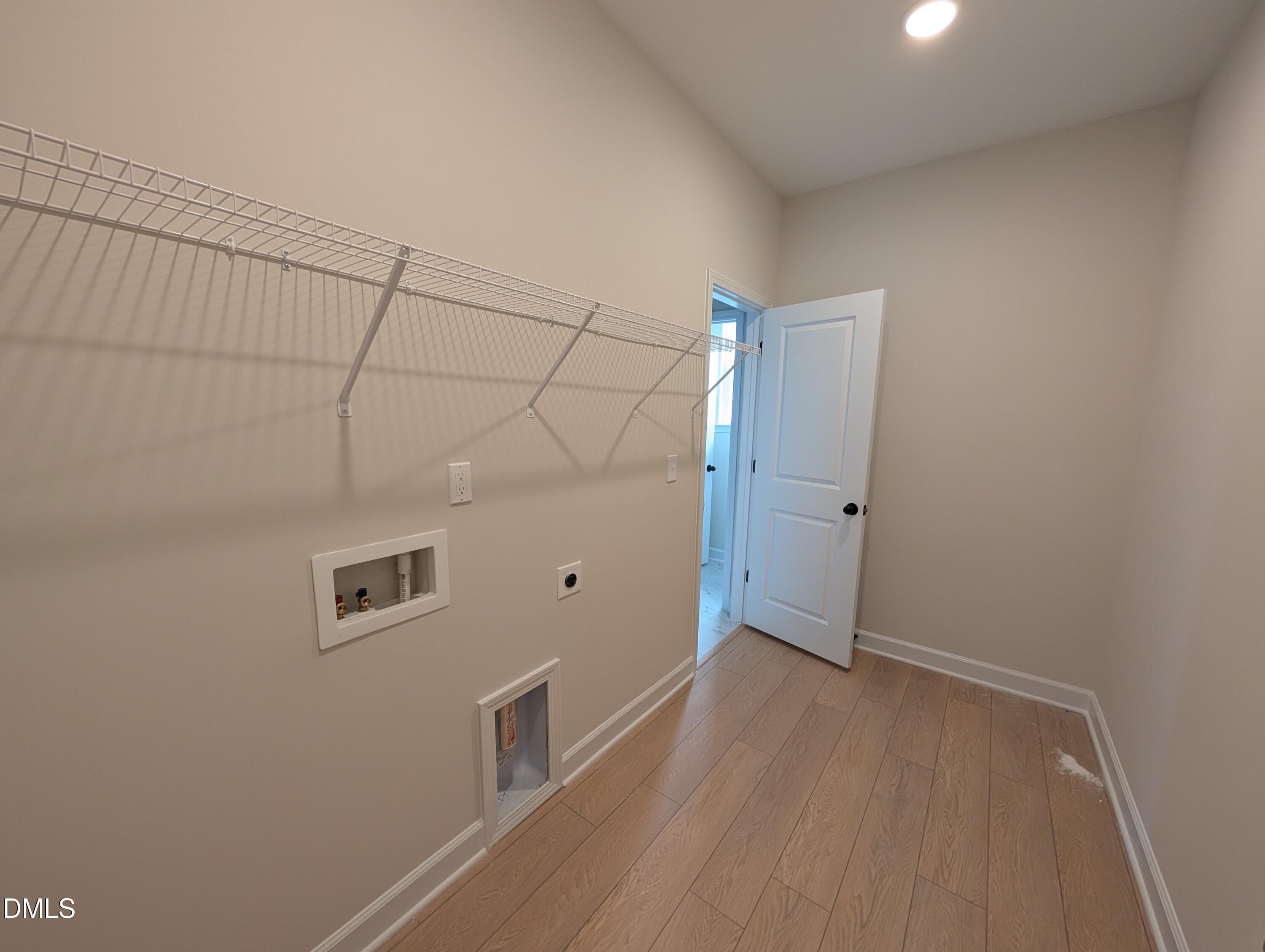 Laundry room with wire shelving, washer hookups, and luxury vinyl plank flooring in Davidson Homes The Ashport M, Wendell Ridge, NC
