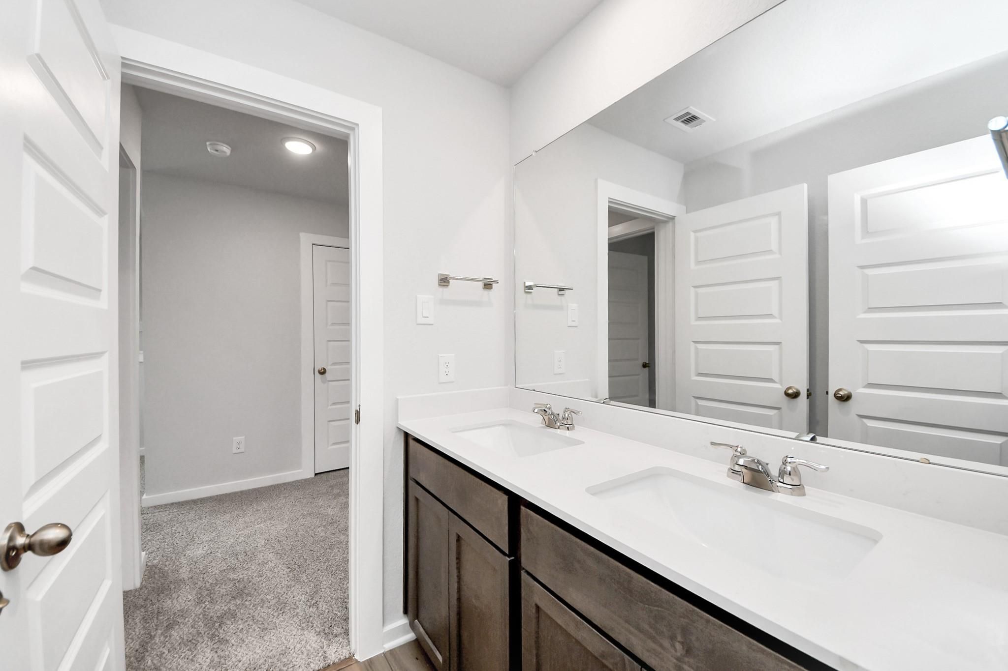 Modern bathroom vanity with double sinks and large mirror in The Sabine E floor plan at Liberty Estates, Cleveland, Texas.
