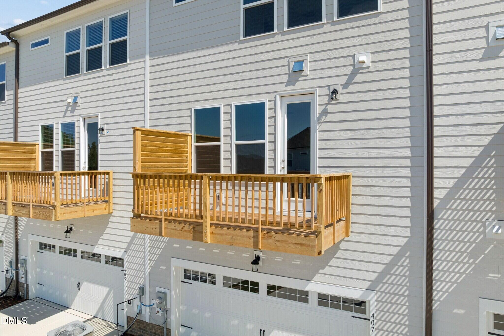Wood balconies above 2-car garages on white townhome exterior at Forestville Yard Townhomes, Knightdale, North Carolina