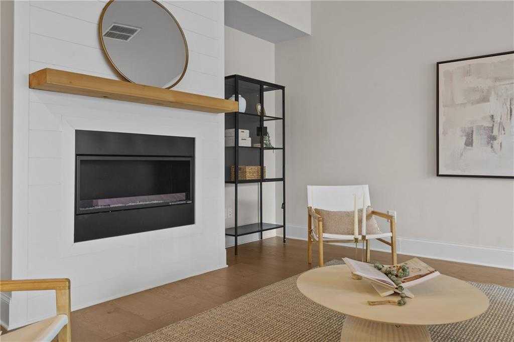 Modern fireplace with wooden mantel, round mirror, and black metal shelving in cozy living room of Davidson Homes Seaside B, Woodstock, GA