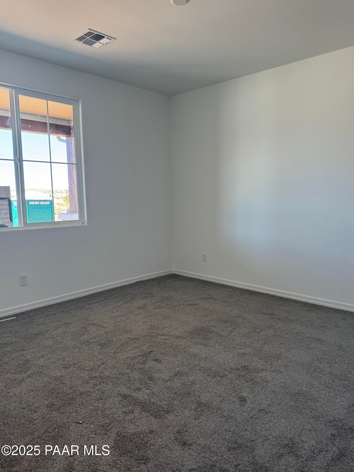 Spacious empty bedroom with white walls, large window, and gray carpet in Davidson Homes The Sunrise II A, Prescott Arizona