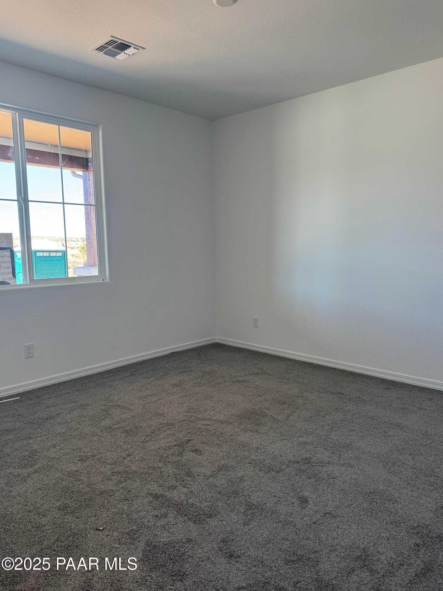 Spacious empty bedroom with white walls, large window, and gray carpet in Davidson Homes The Sunrise II A, Prescott Arizona