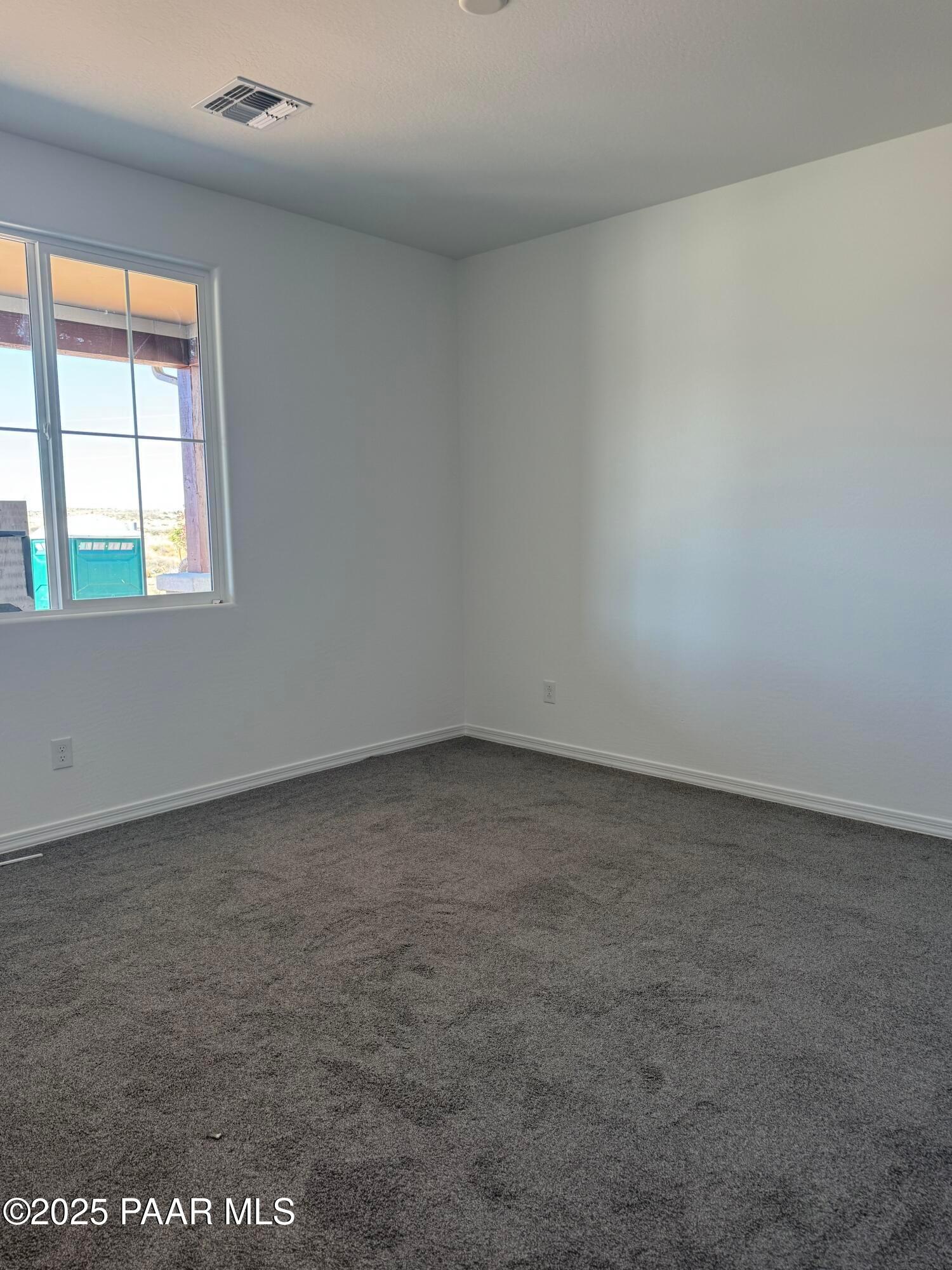 Spacious empty bedroom with white walls, large window, and gray carpet in Davidson Homes The Sunrise II A, Prescott Arizona