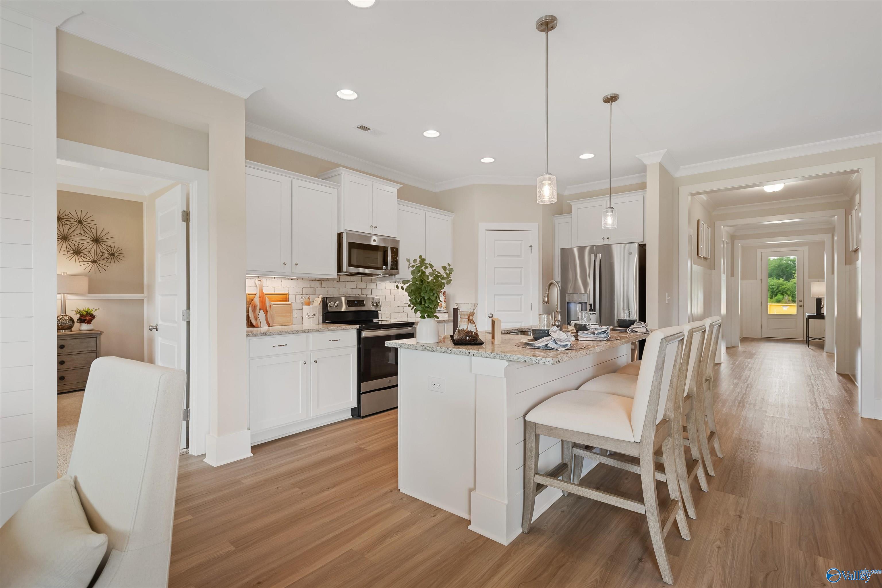 Modern open-concept kitchen with white shaker cabinets, stainless steel appliances, and spacious island in Davidson Homes The Everett, New Market, Alabama