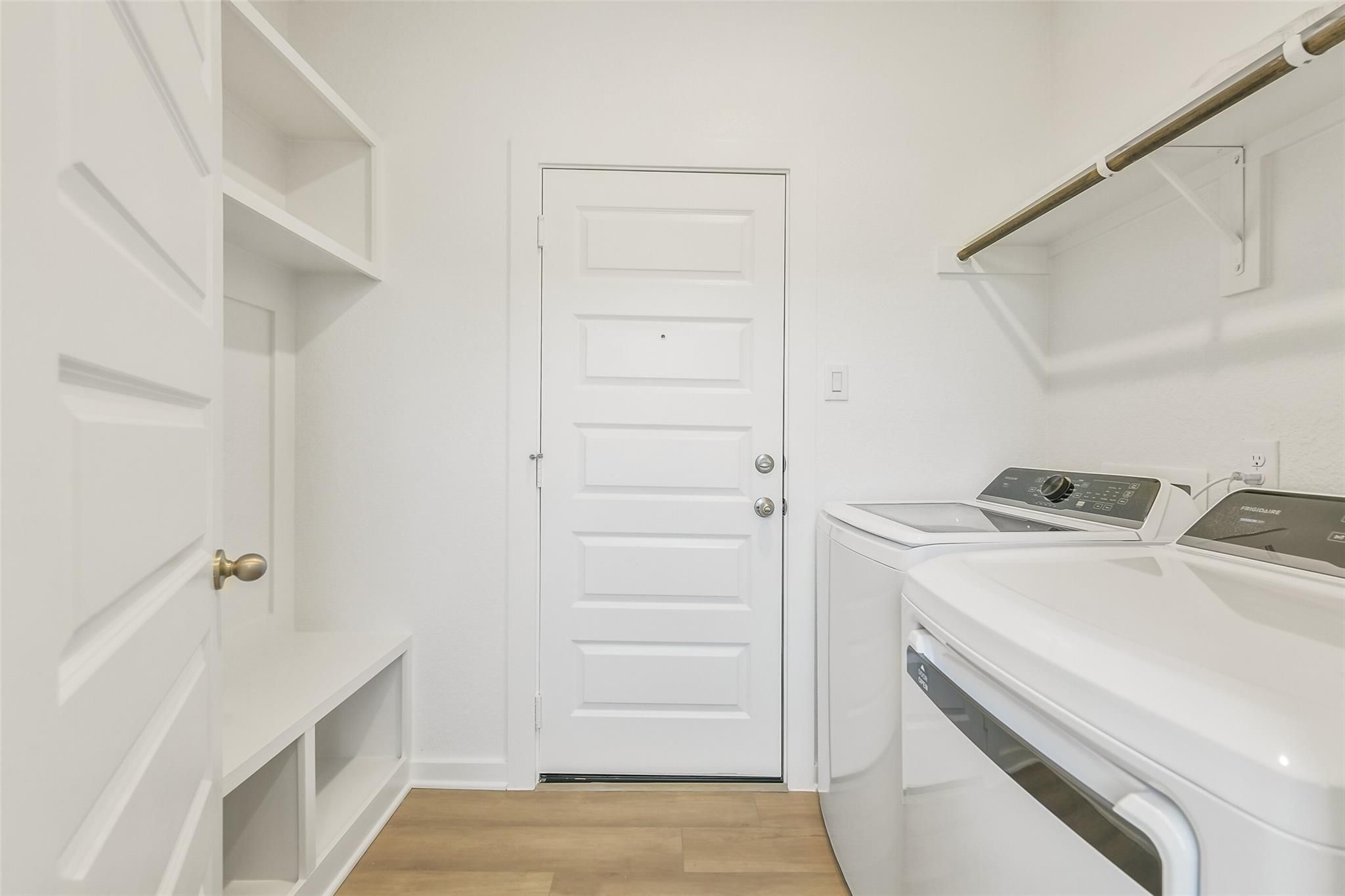 Spacious laundry room with white washer dryer, built-in shelves, bench in 5-bedroom Davidson Homes San Marcos E, Cleveland Texas