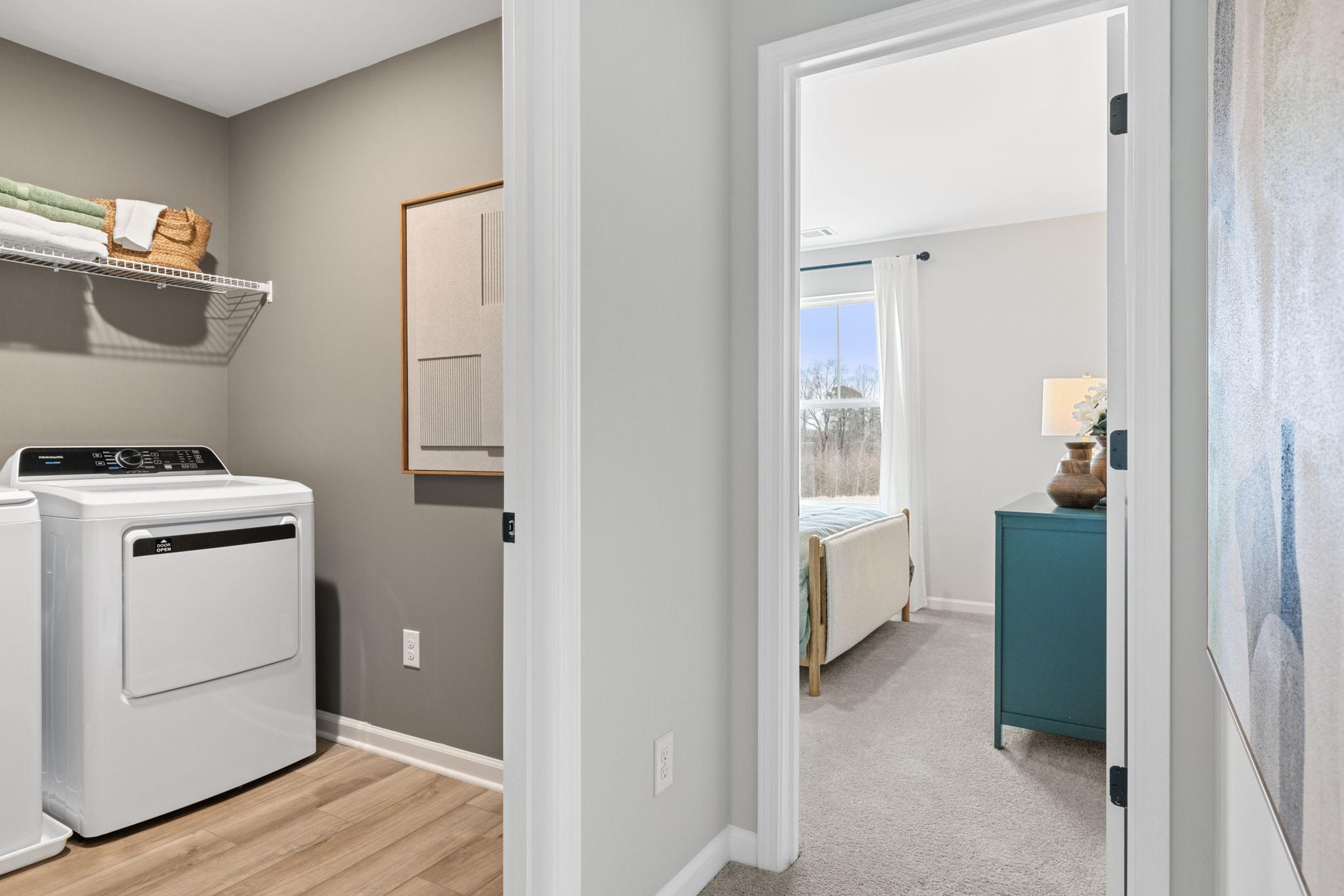 Spacious laundry room with washer dryer shelving adjacent to bedroom in Cedar Farms Winder GA by Davidson Homes