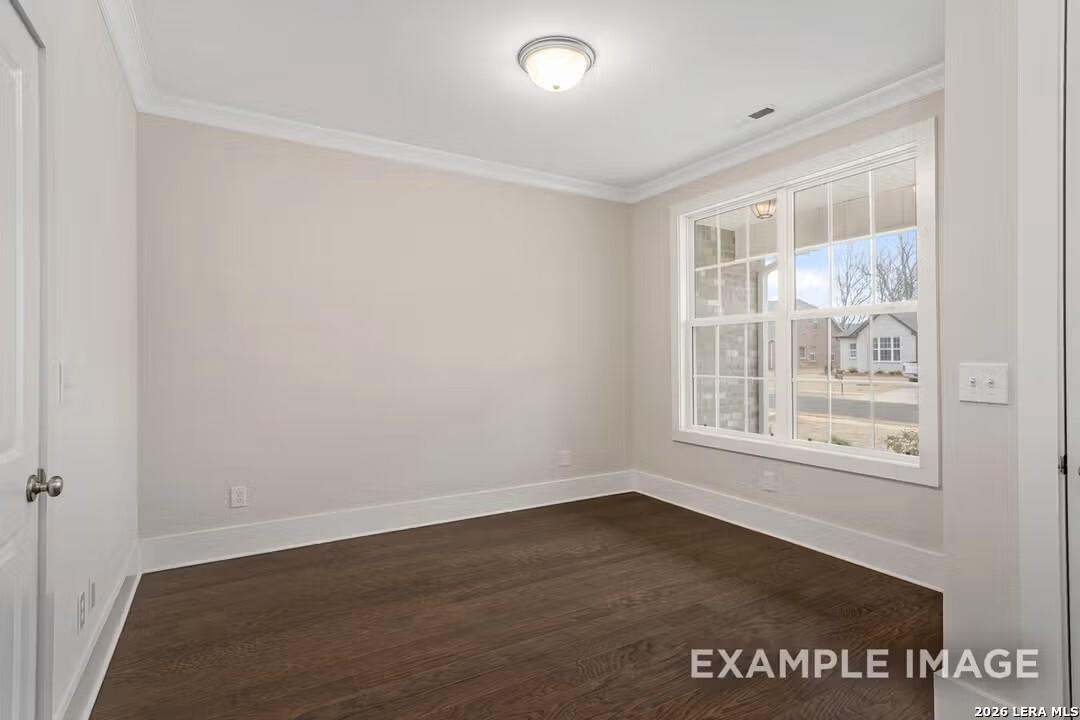 Empty bedroom featuring beige walls, hardwood floors, and large window with neighborhood view in Davidson Homes The Rockford F, Castroville, Texas