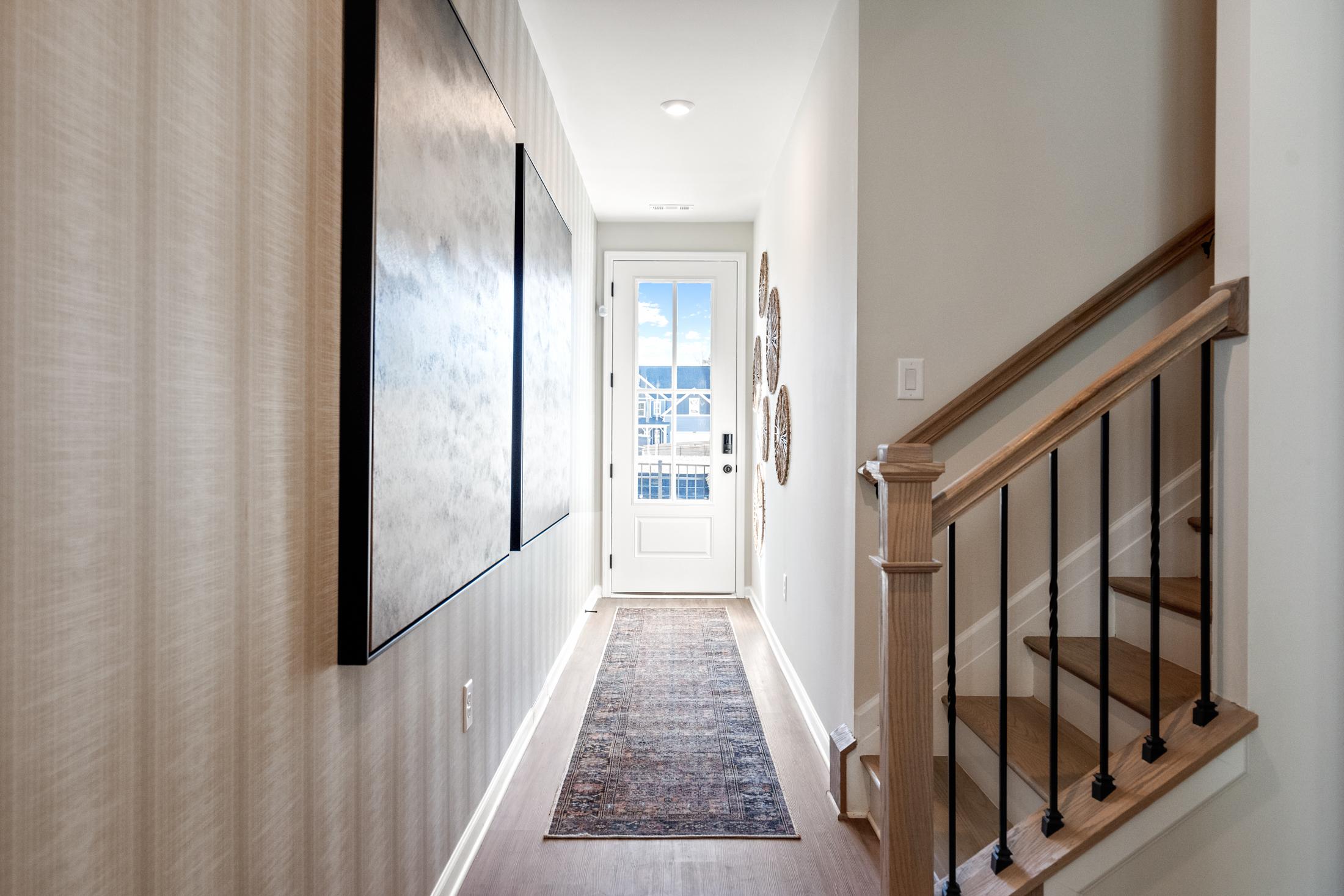 Spacious hallway in The Marion A by Davidson Homes featuring large abstract artwork, runner rug, and oak staircase to upper floor