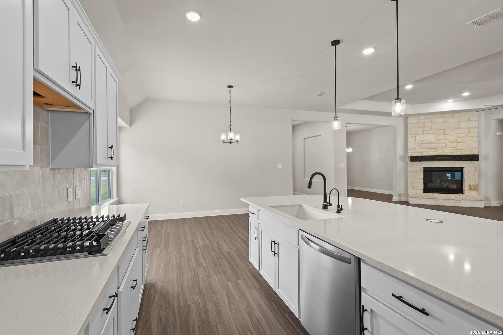 Modern kitchen with white cabinets, quartz island, and gas cooktop in The Summerlin B floor plan at Potranco Oaks.