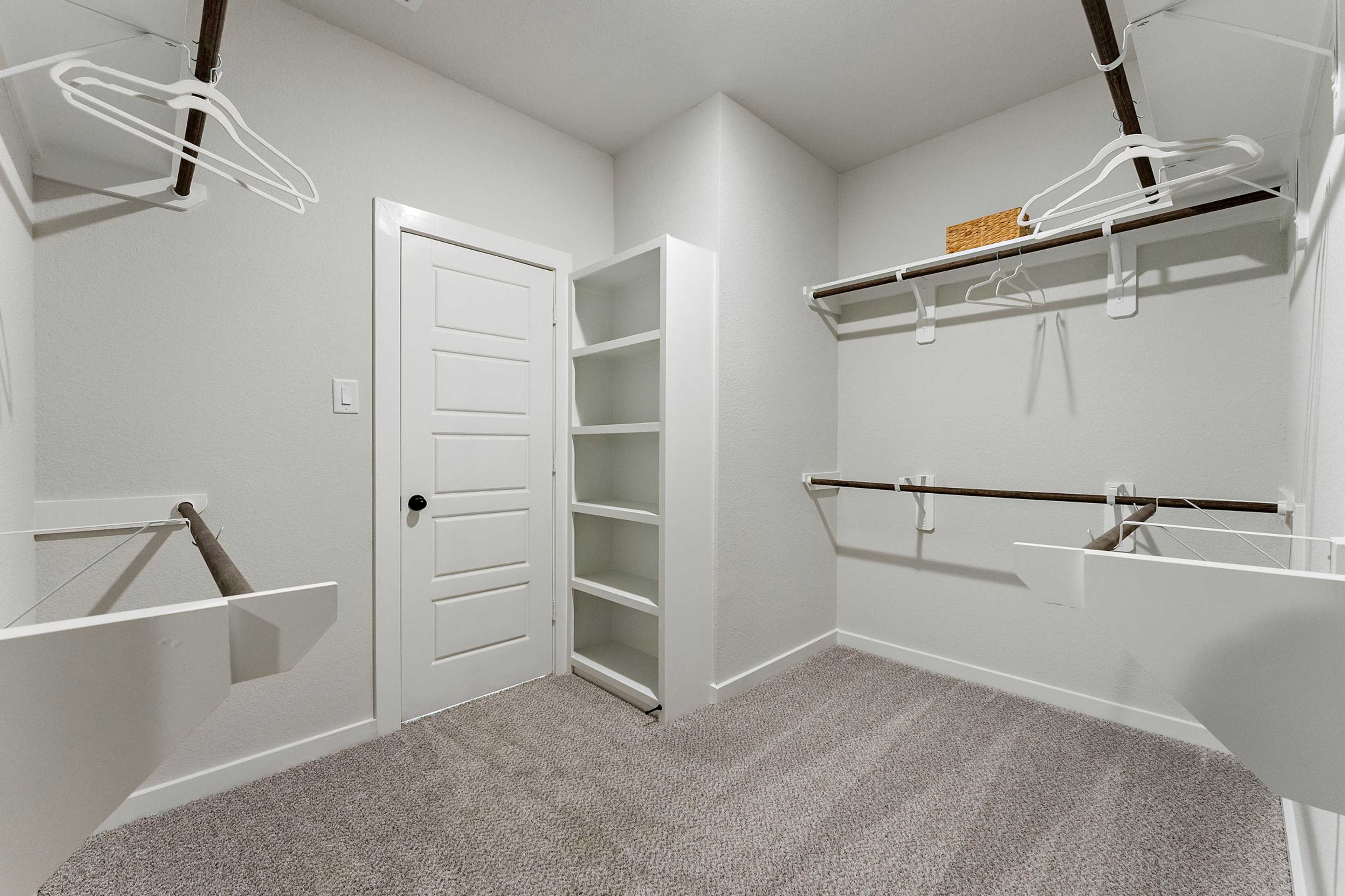 Spacious walk-in closet at Sundance Cove in Crosby, Texas with built-in shelves, hanging rods, and vanity sink by Davidson Homes
