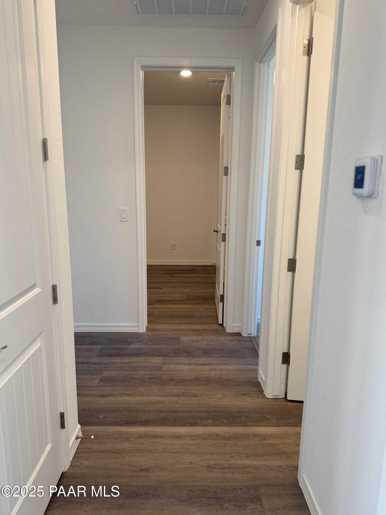 Bright hallway with hardwood floors, white trim doors, and open entryways in Davidson Homes The Sunrise II A, Prescott, Arizona