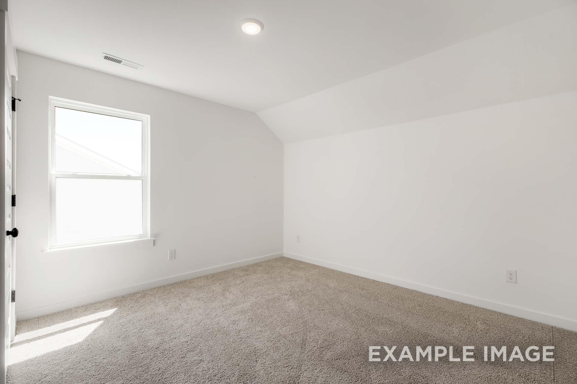 Spacious empty bedroom in The Ash C home with vaulted ceiling, large gable window, neutral carpet, and white walls