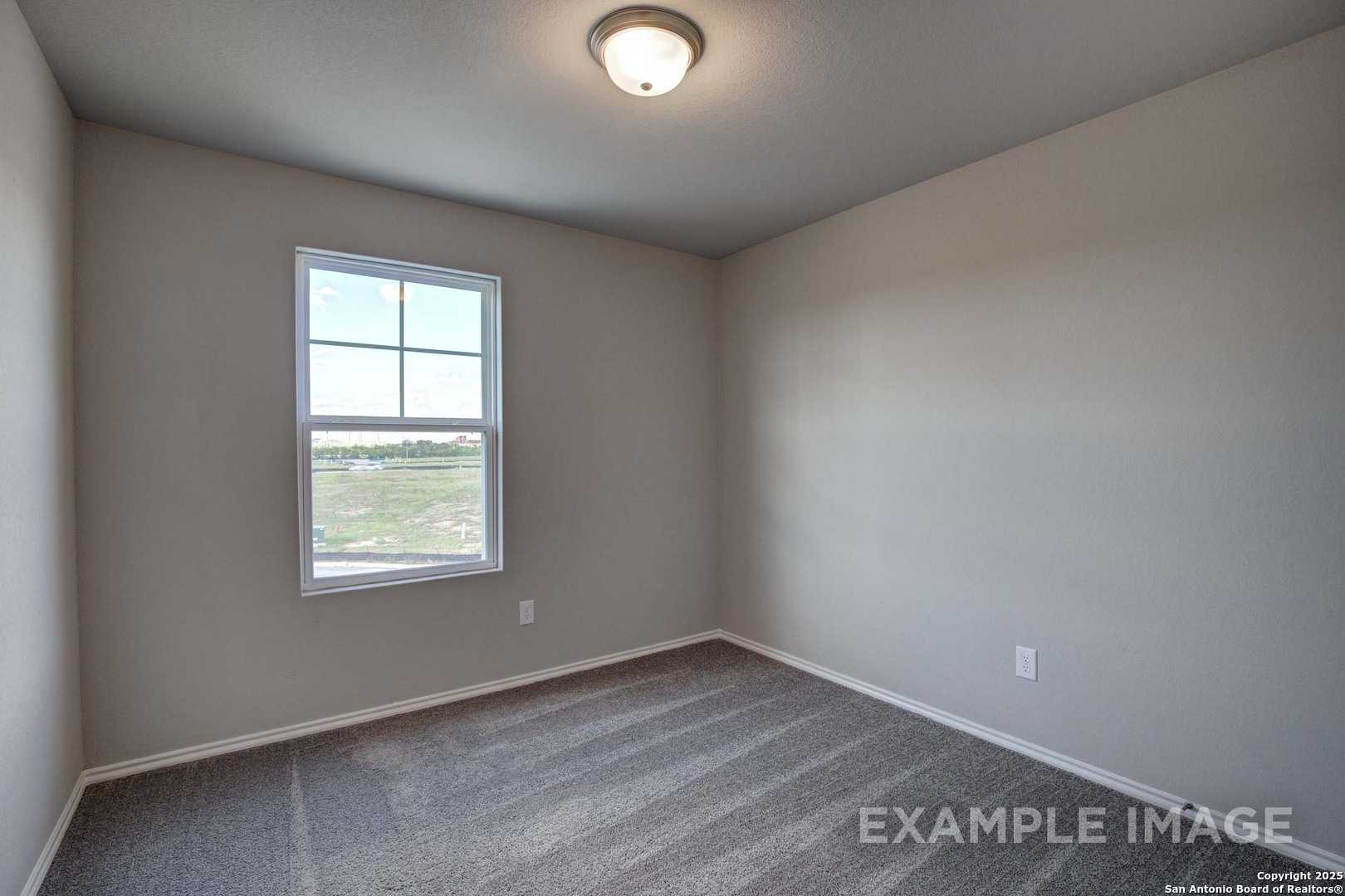 Empty bedroom with neutral beige walls, gray carpet flooring, and large window with prairie view in Davidson Homes The Blanco C, San Antonio